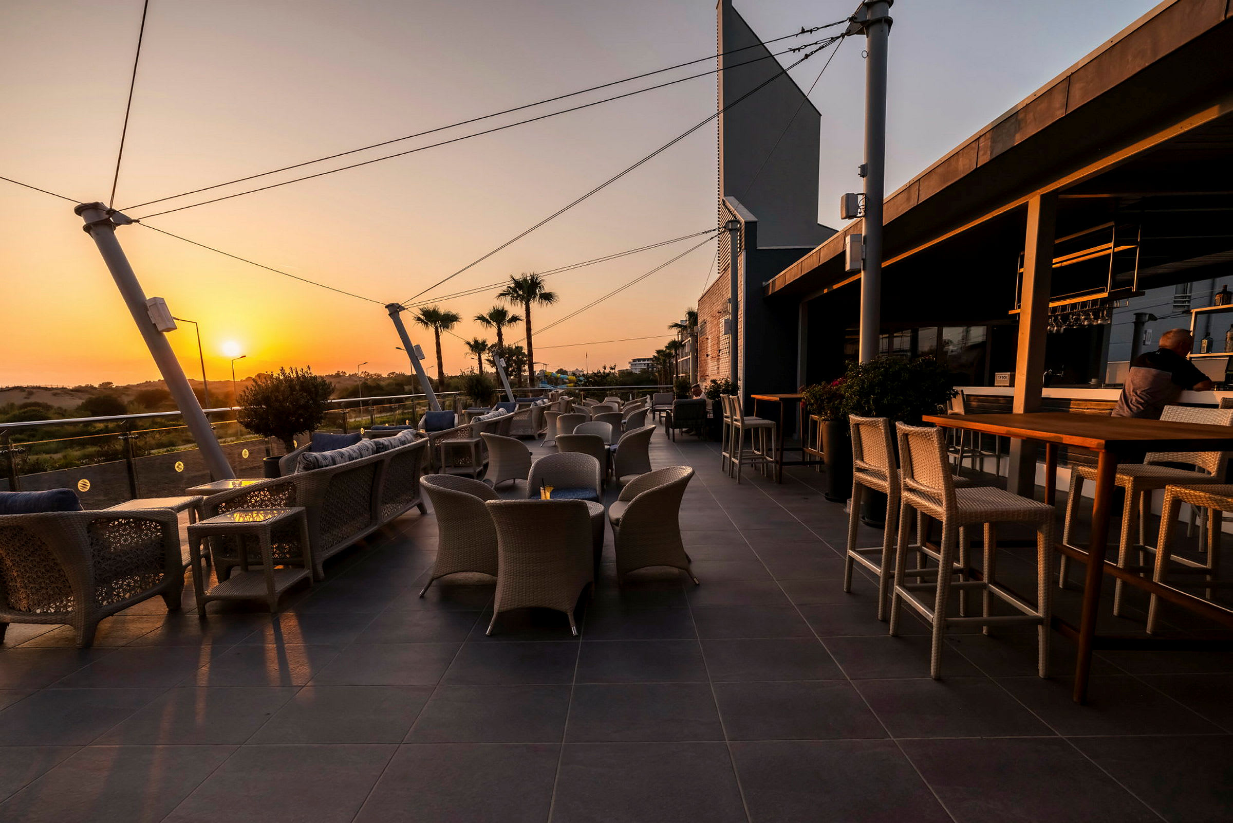 Utendørs terrasse med sittegrupper og utsikt over landskapet ved solnedgang. (AI-generert tekst)