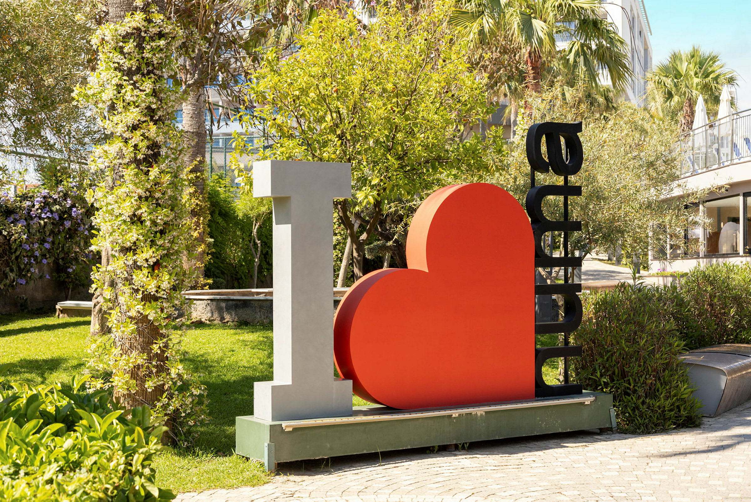 Skulpturen viser teksten "I ♡ Alanya" omgitt av en frodig hage. (AI-generert tekst)
