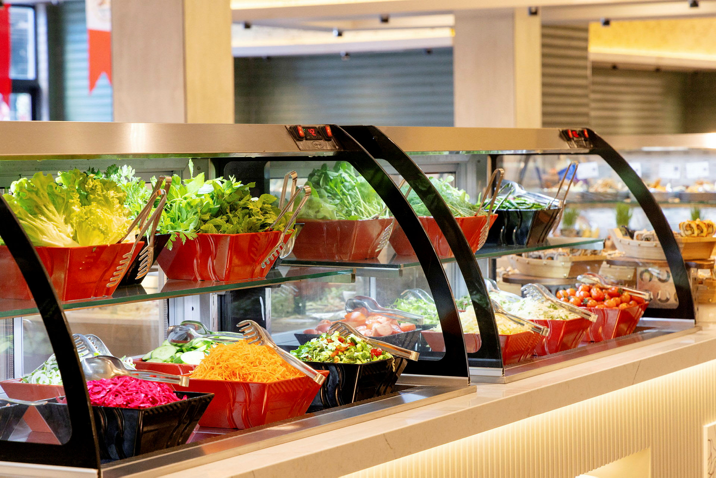En salatbuffé med ulike grønnsaker og salatingredienser, arrangert i glass- og plastboller. (AI-generert tekst)