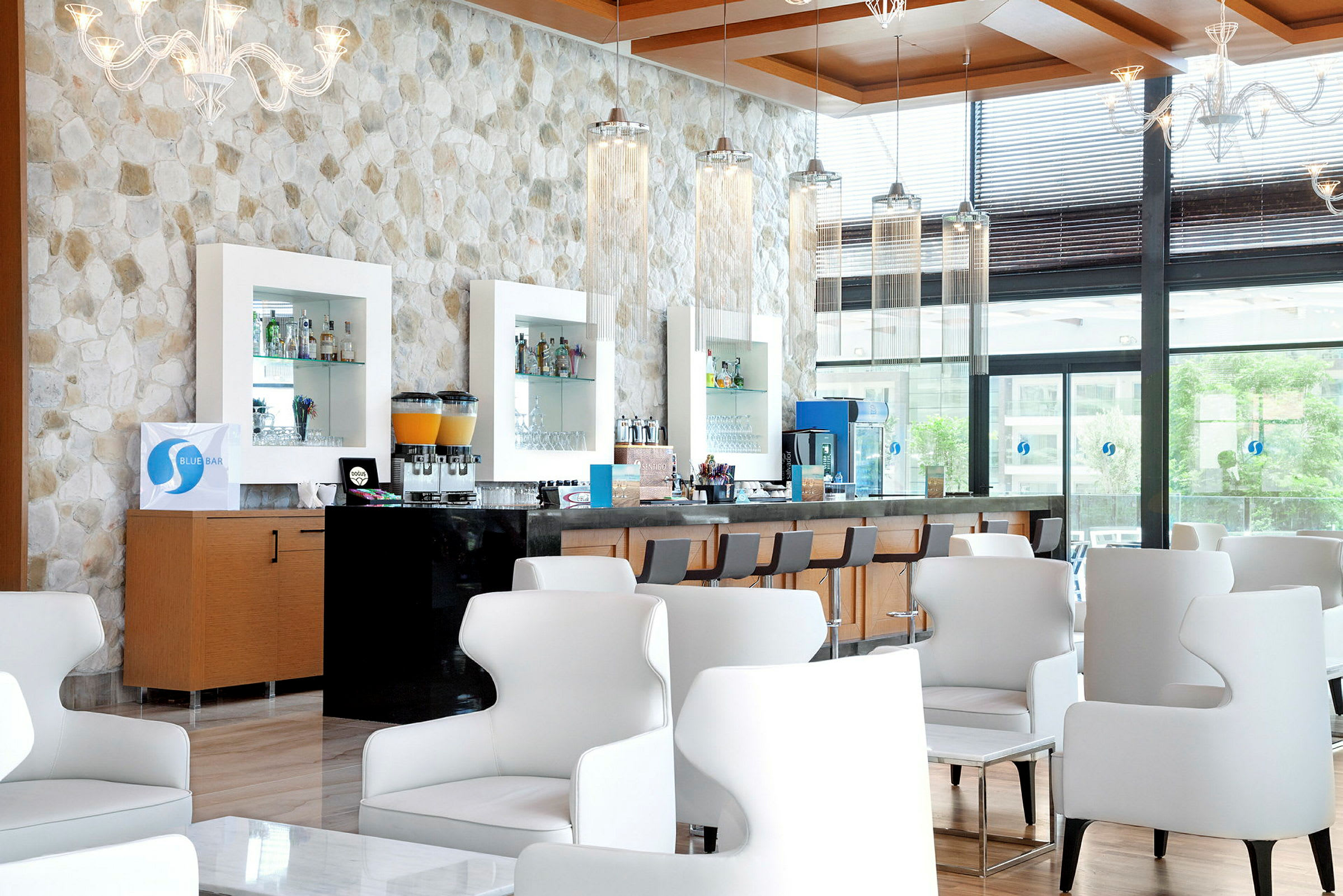 En moderne barlounge med hvite stoler og en vegg av stein. (AI-generert tekst)