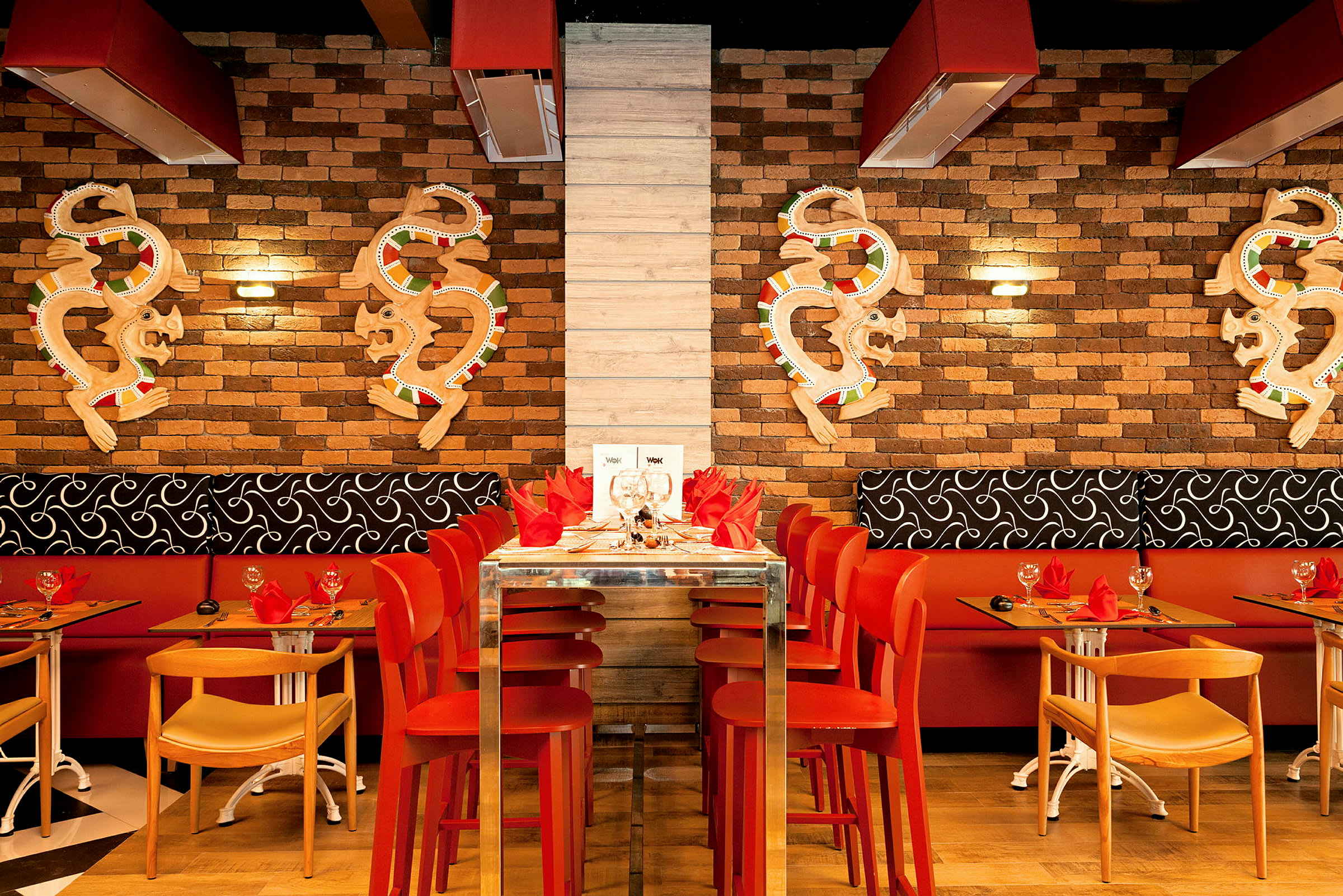 En restaurantinnredning med røde stoler og en mursteinsvegg dekorert med kunstverk. (AI-generert tekst)