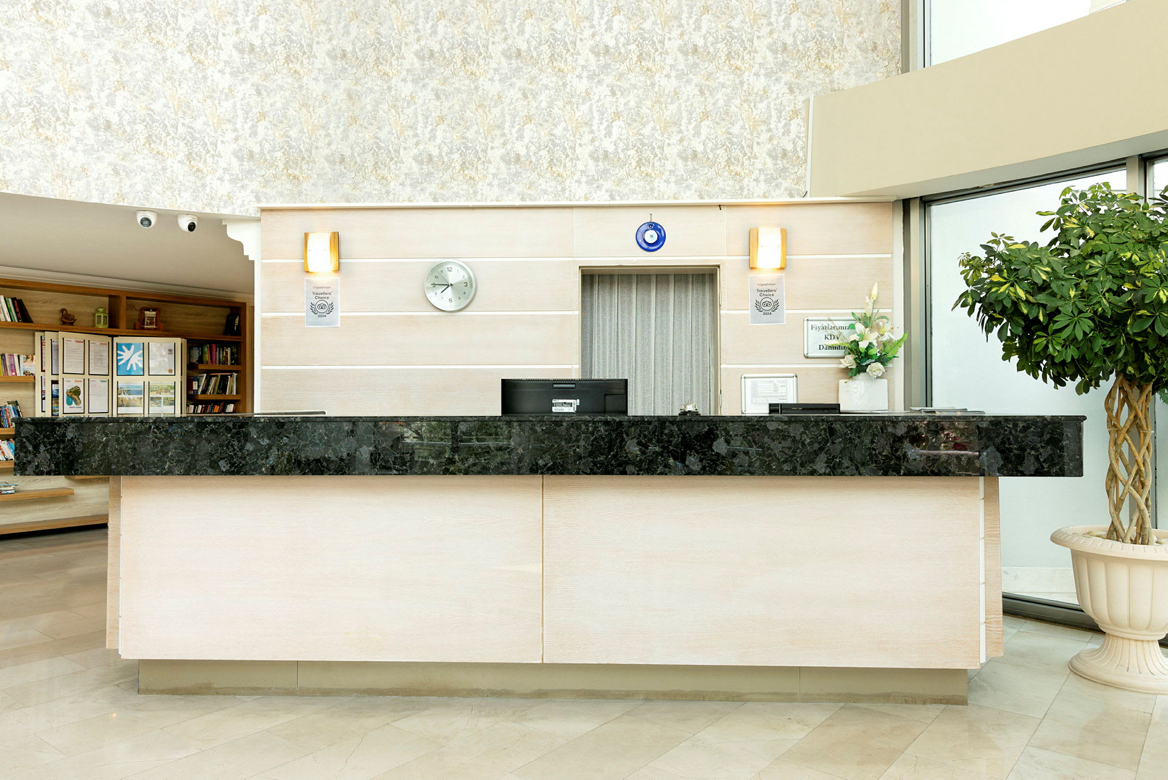 Hotellresepsjon med svart marmorarbeidsflate, beige vegger og en grønn plante til høyre. (AI-generert tekst)