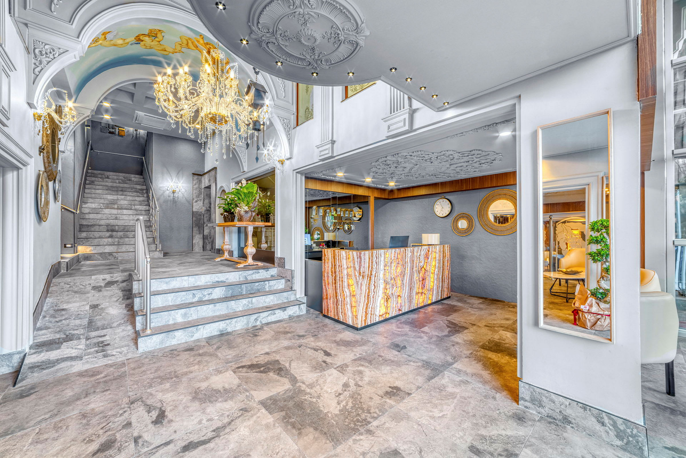 En hotellresepsjon med elegant marmorgulv, en dekorativ krystall-lysekrone og utsmykkede vegger. (AI-generert tekst)