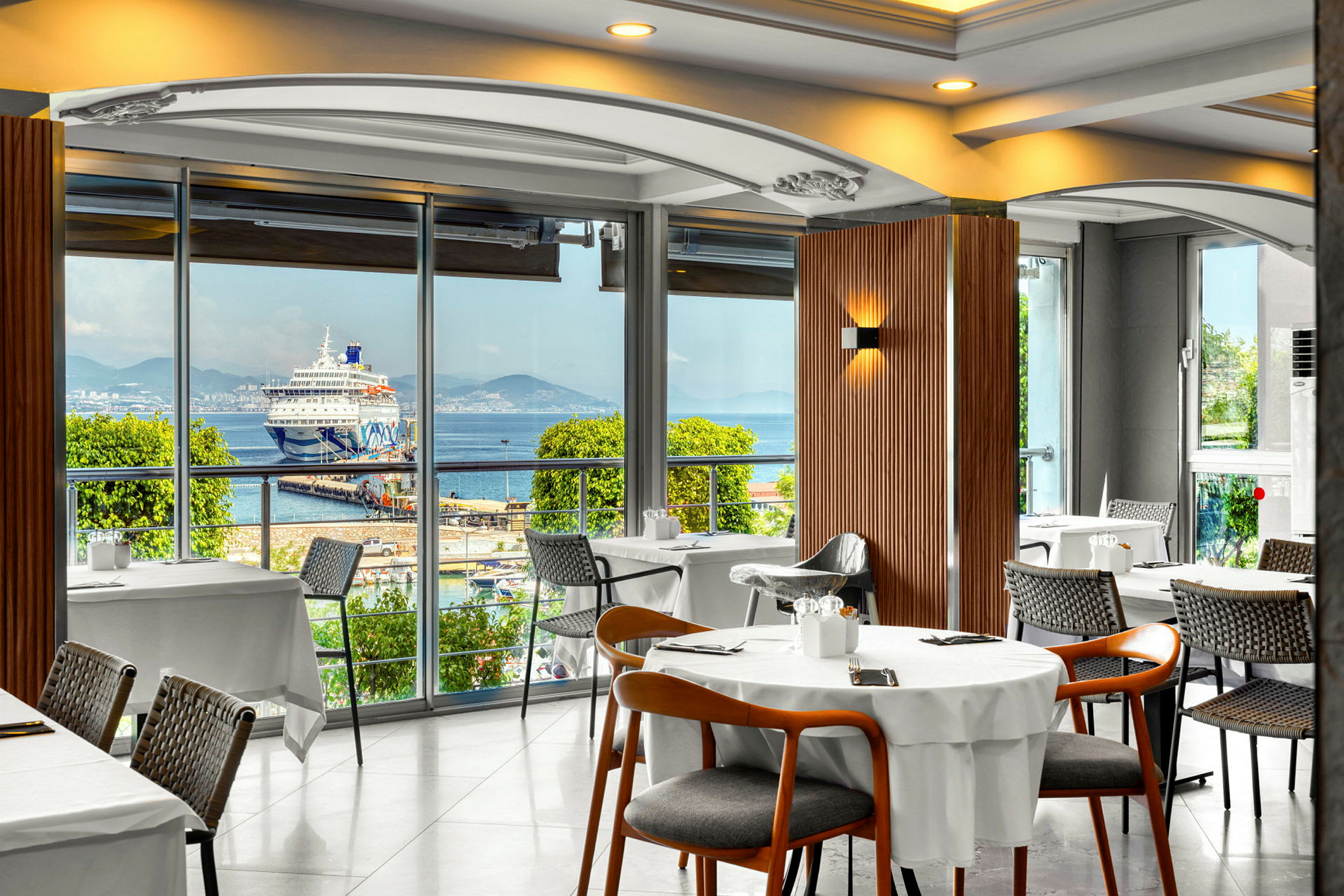 Restaurant med utsikt mot et cruiseskip ved en havn. (AI-generert tekst)