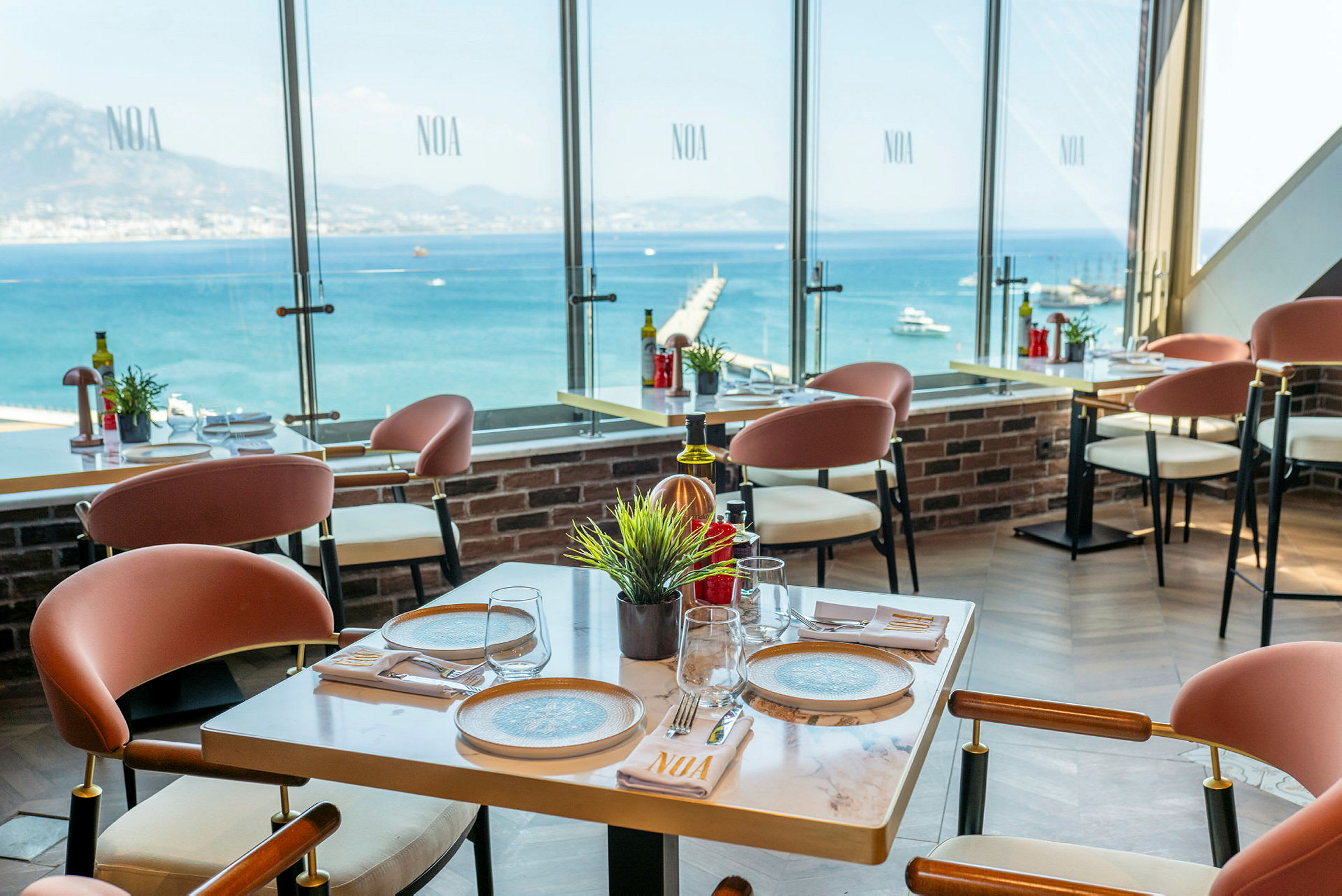 Restaurant med moderne møbler og utsikt over havet gjennom store vinduer. (AI-generert tekst)