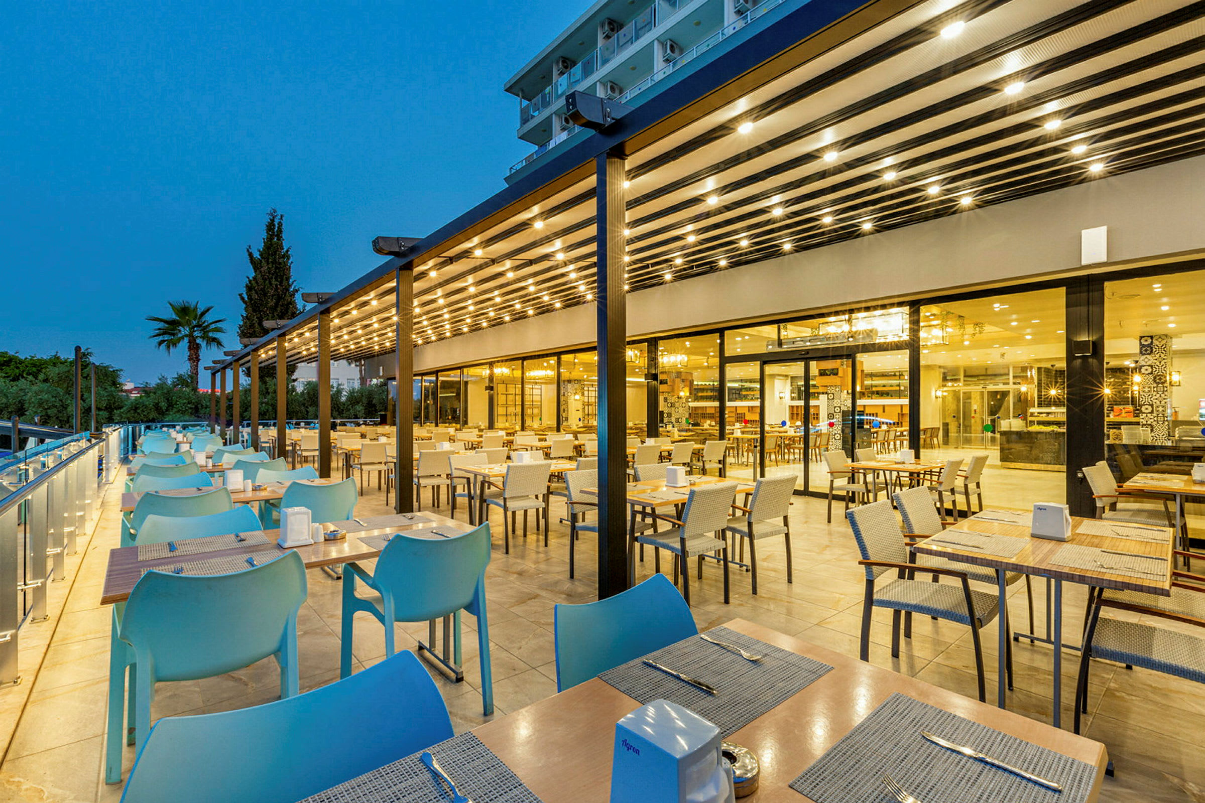 Uteserveringen til en moderne restaurant på kveldstid. (AI-generert tekst)