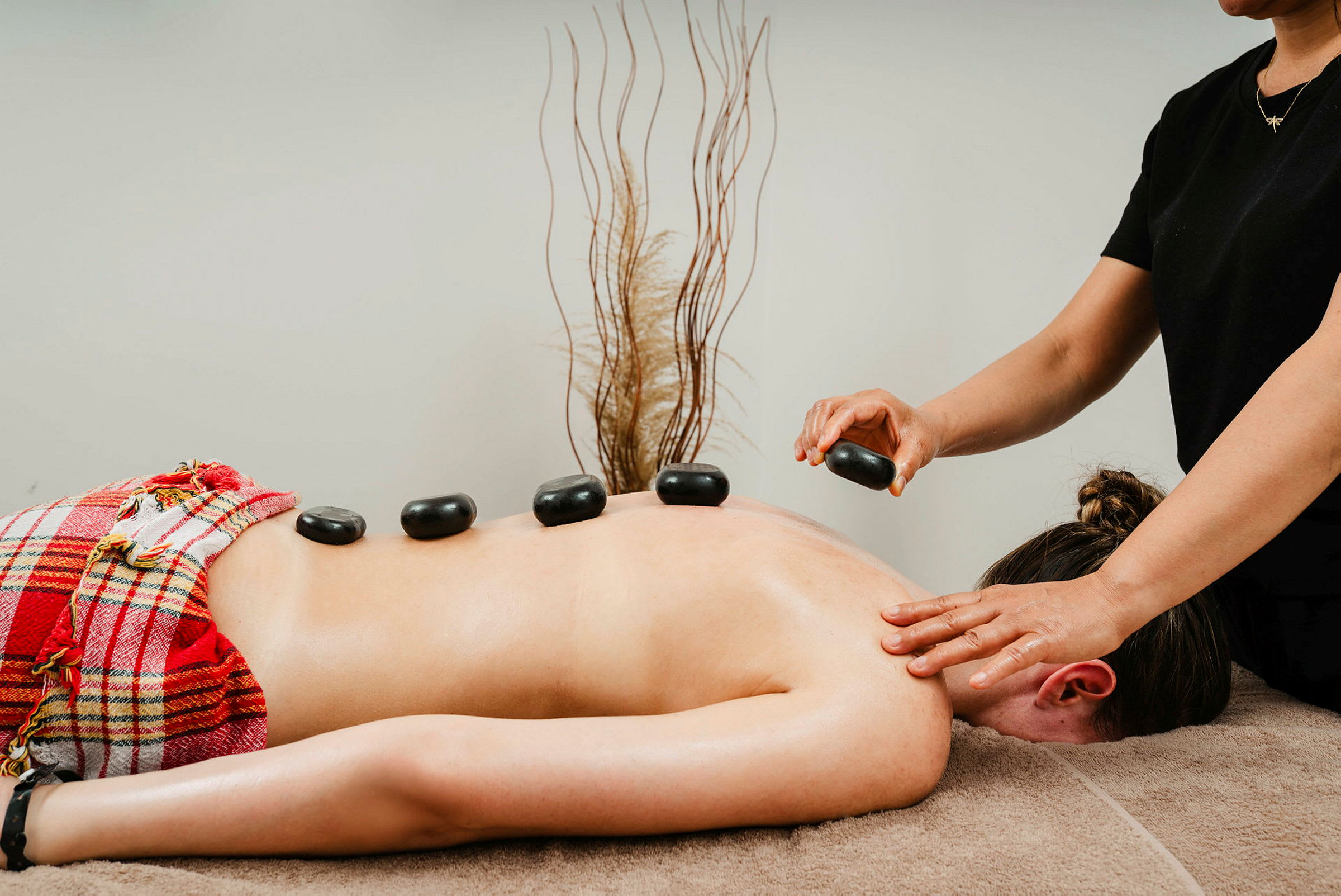 En person får hot stone-massasje med steiner plassert på ryggen. (AI-generert tekst)