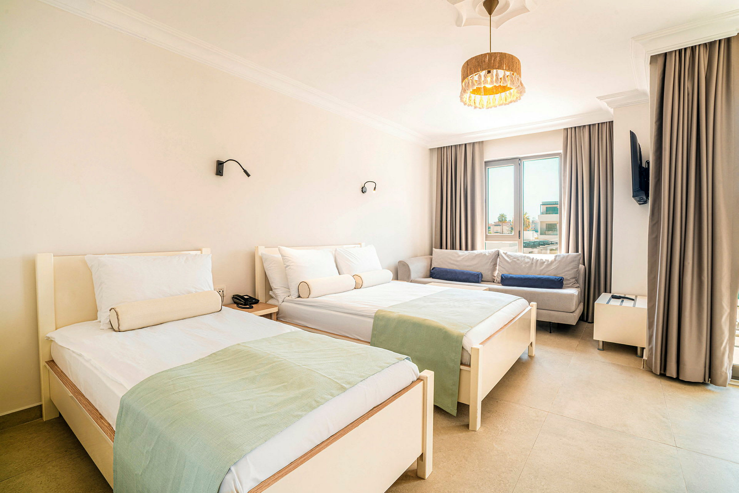 Et hotellrom med to enkeltsenger, en sofa og et vindu. (AI-generert tekst)