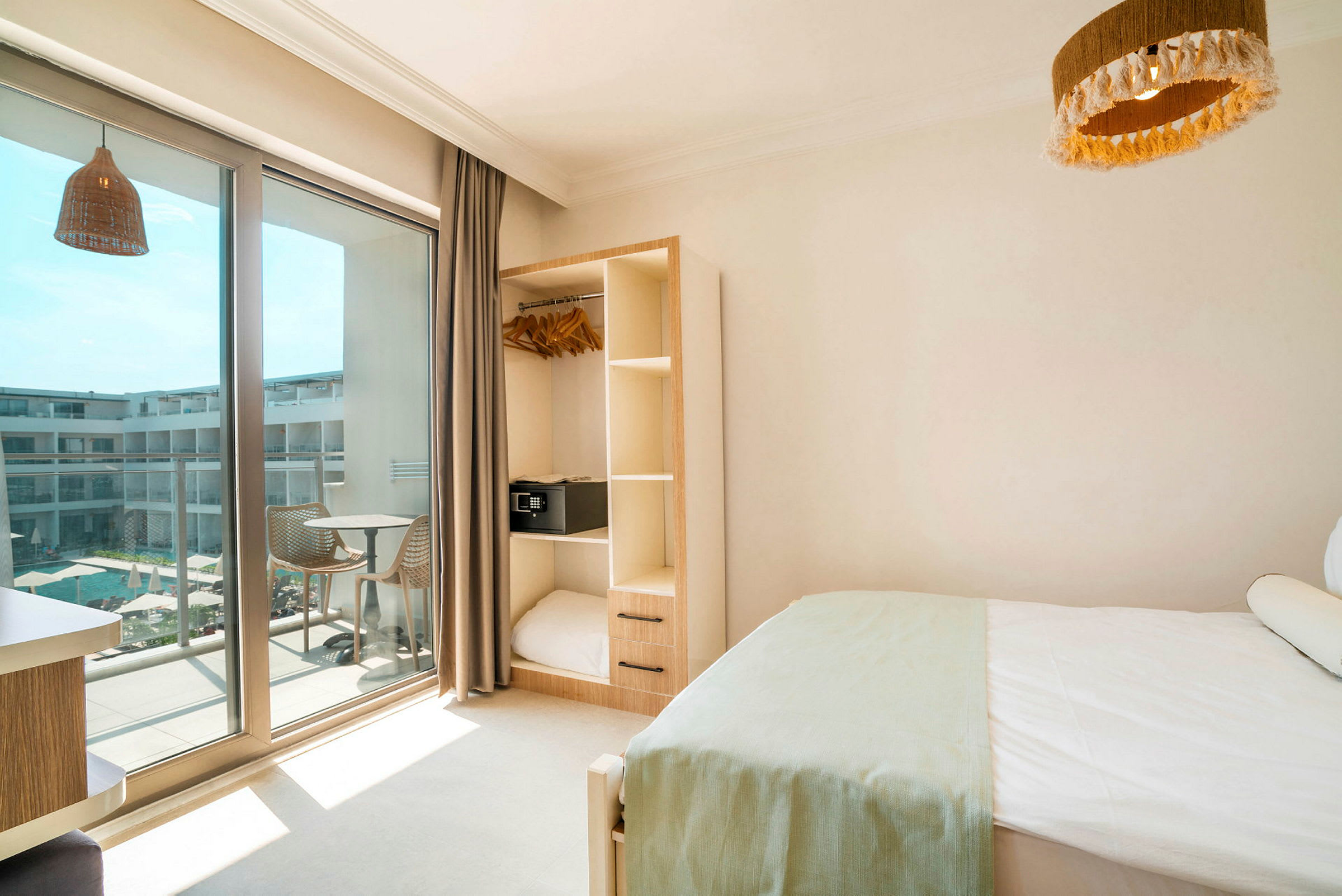 Hotellrom med seng, garderobe og balkong som vender mot et basseng. (AI-generert tekst)
