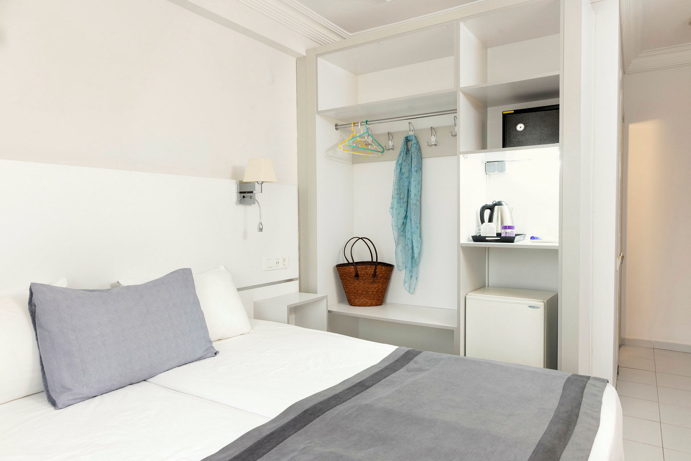 Hotellrom med seng, garderob og en minikjøleskap. (AI-generert tekst)