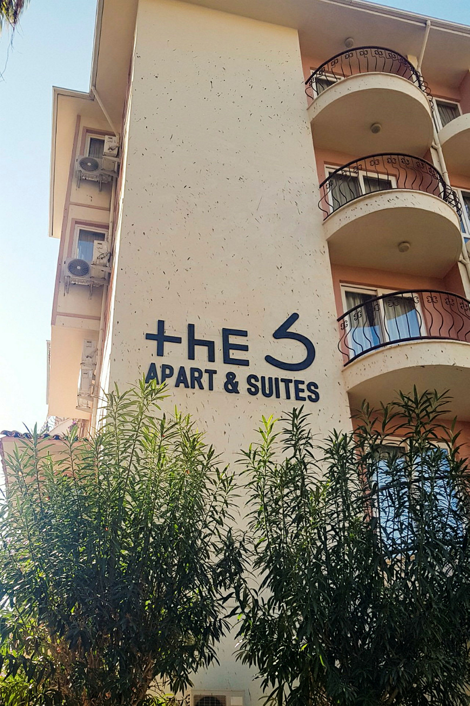 Bygning med et skilt der det står "The S Apart & Suites", omgitt av trær. (AI-generert tekst)