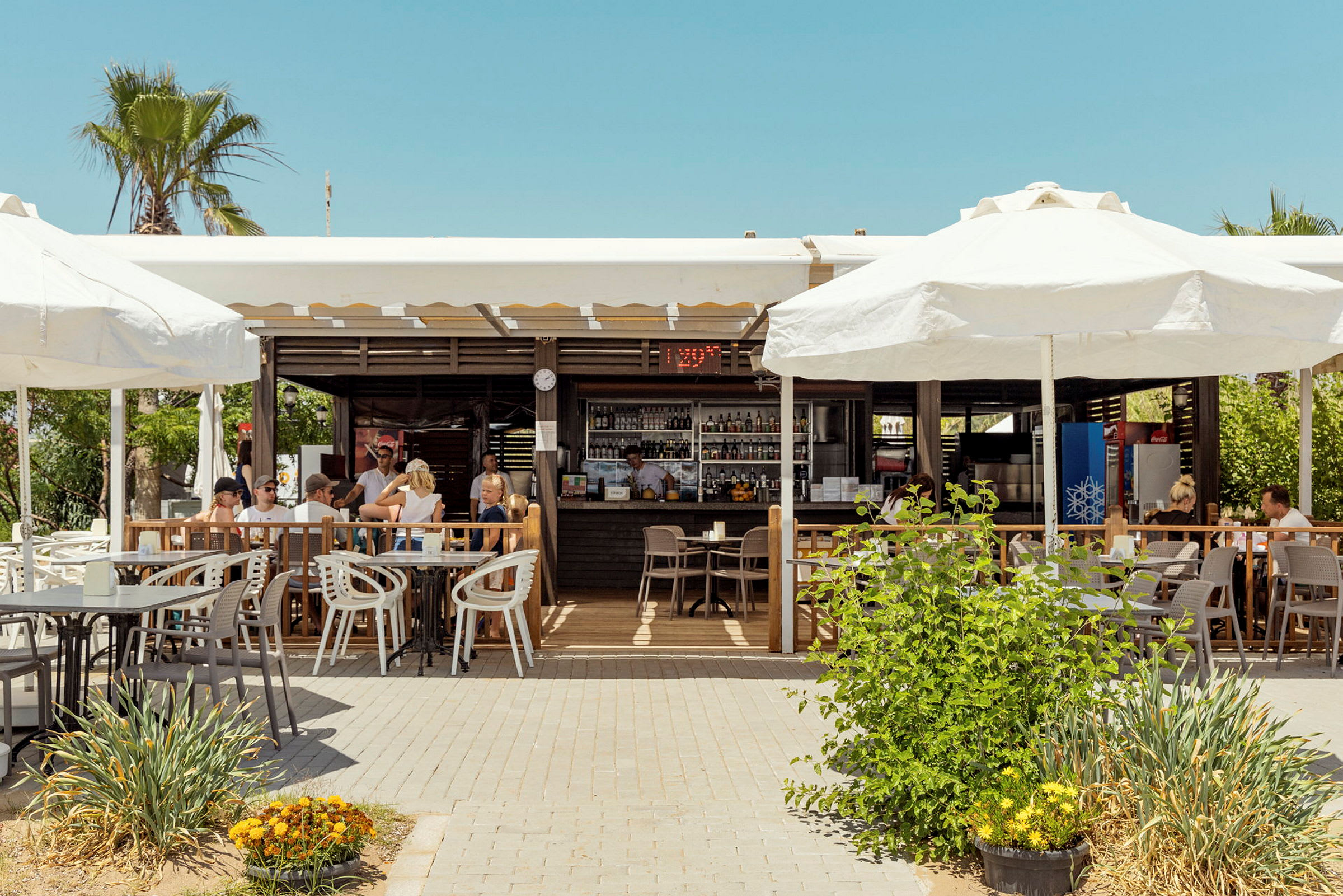 Utendørsrestaurant med parasoller og sittegrupper på terrasse. (AI-generert tekst)
