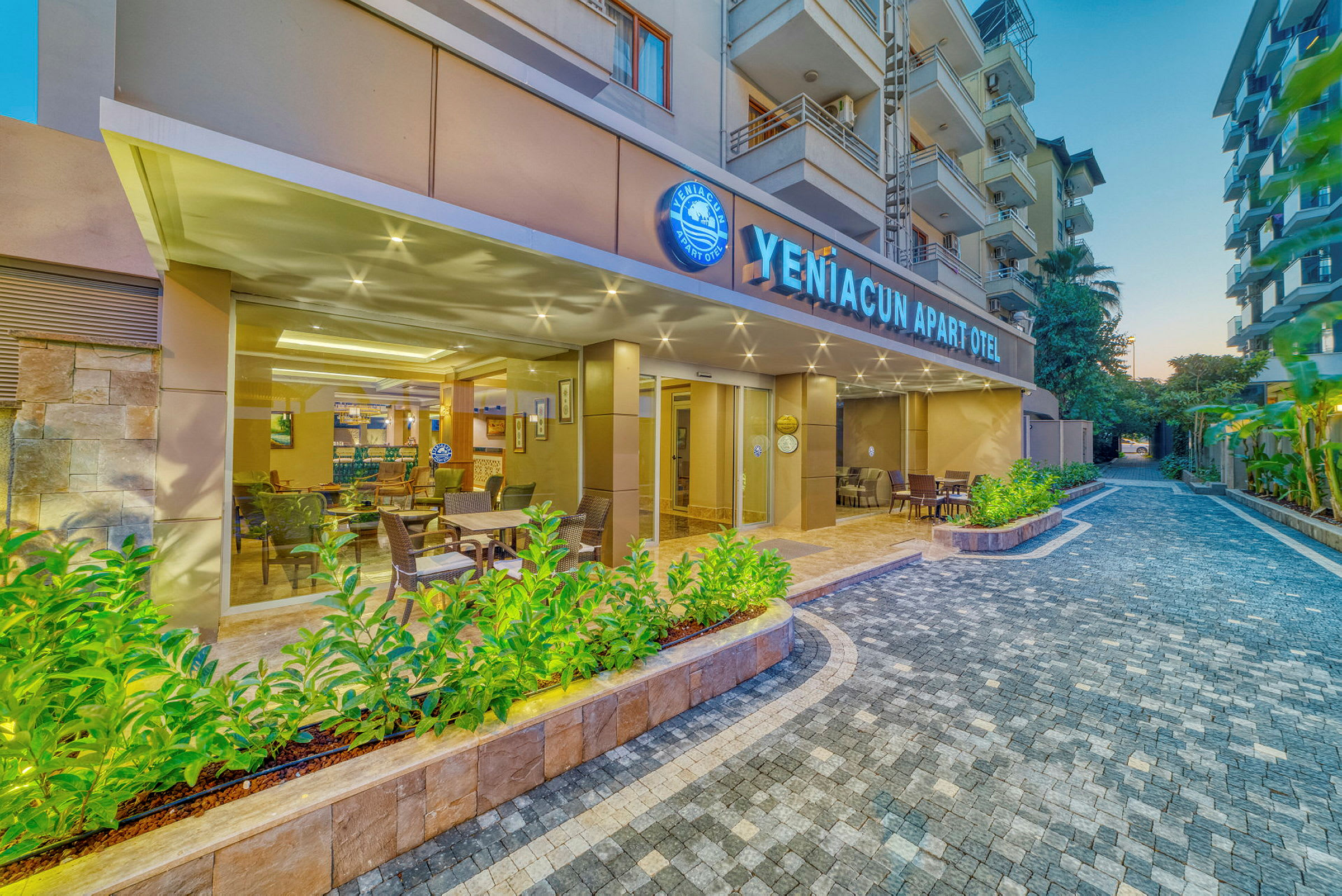 Eksteriør av YenĂ?acun Apart Otel med utendørs sitteplasser og grøntområder. (AI-generert tekst)
