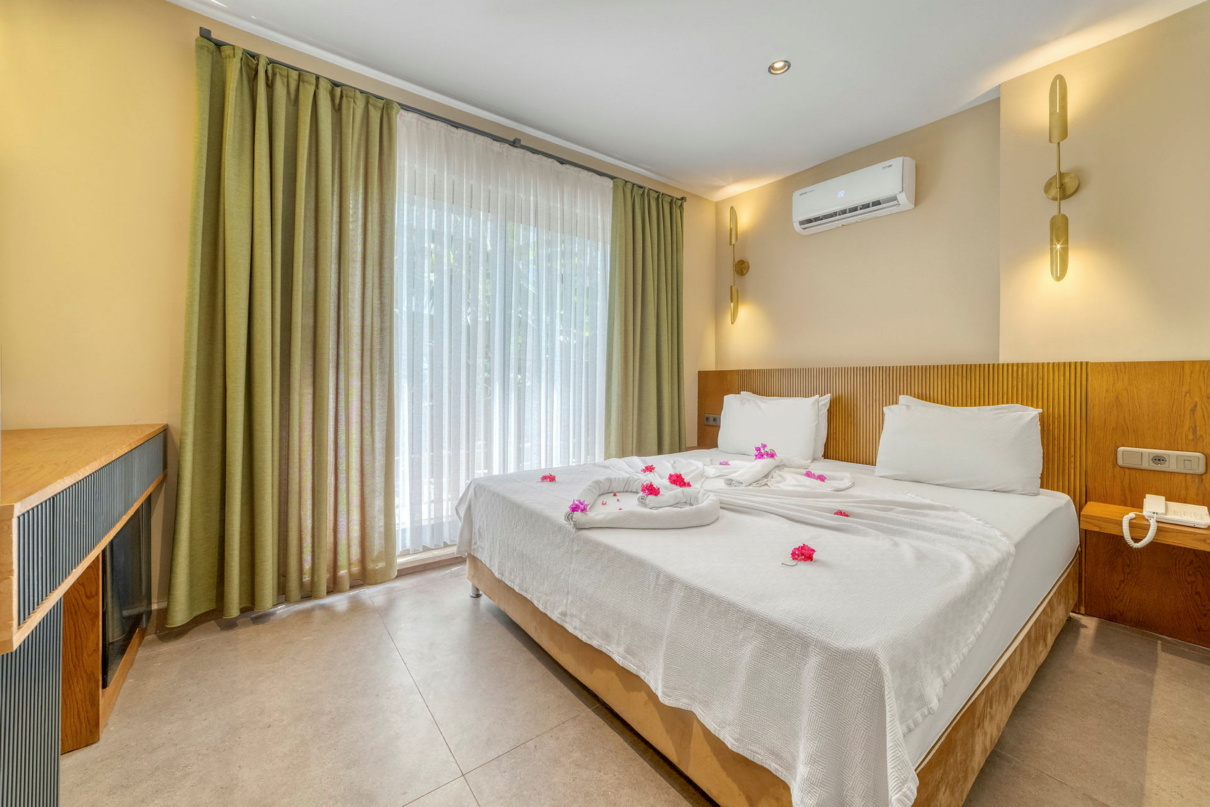 Hotellrom med en dobbeltseng redd opp med hvite laken og dekorert med blomster. (AI-generert tekst)