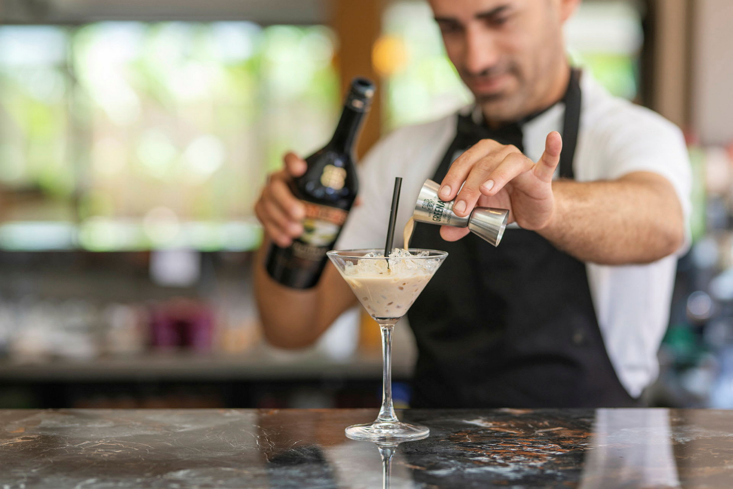 En bartender som lager en cocktail med fløtebasert likør. (AI-generert tekst)