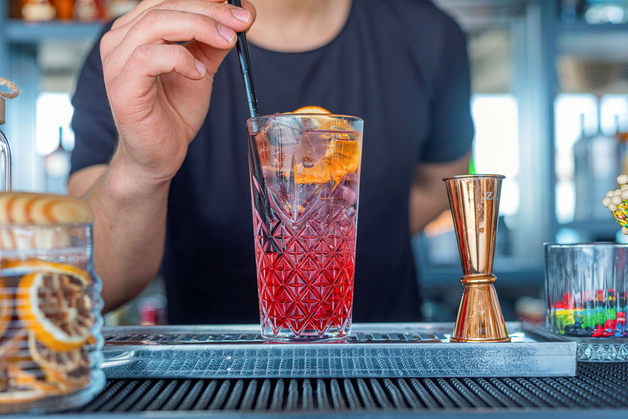 En drikk med is og et sugerør holdes ved en bar. (AI-generert tekst)