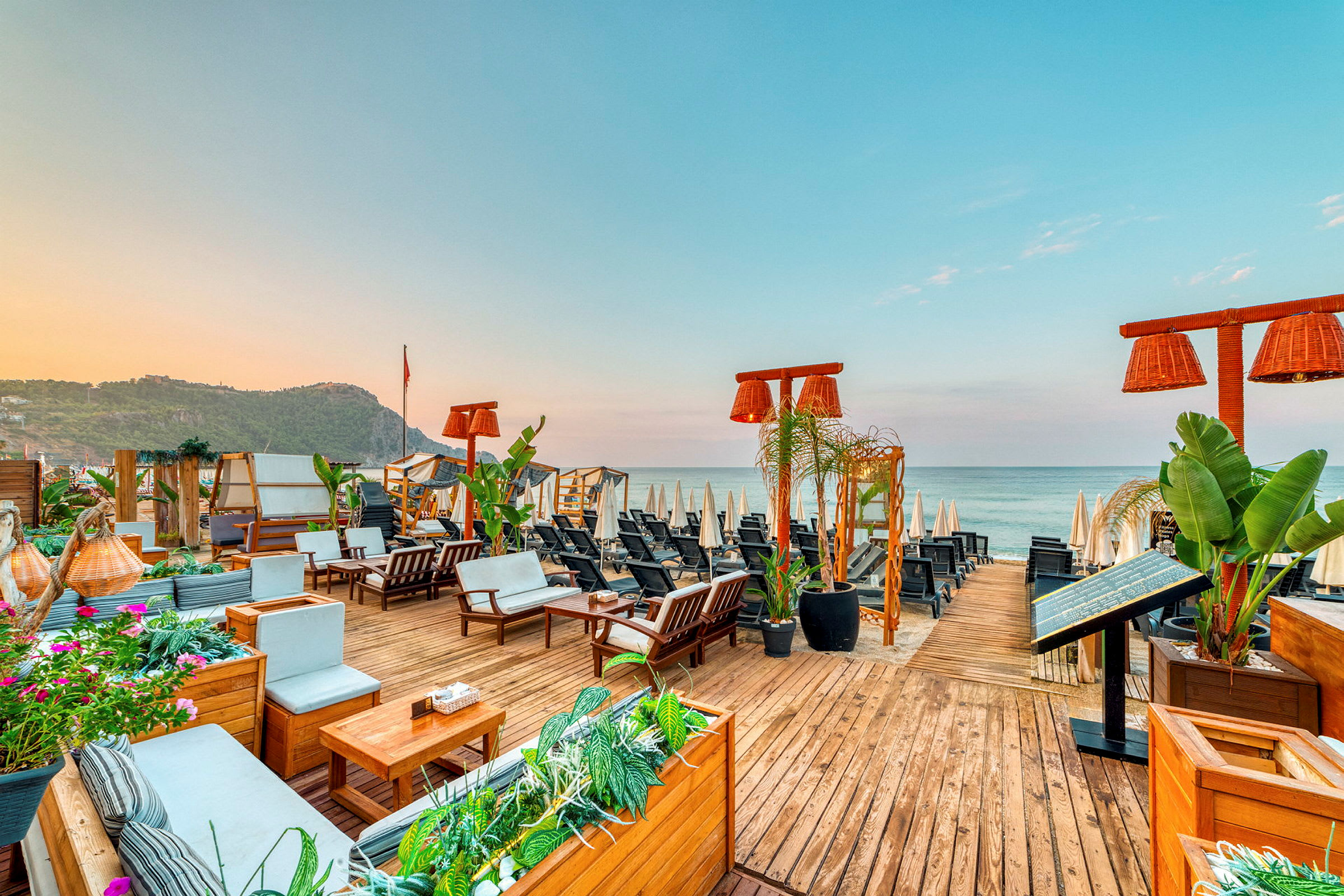 Utsikt over en strandbar med utemøbler og parasoller ved havet. (AI-generert tekst)