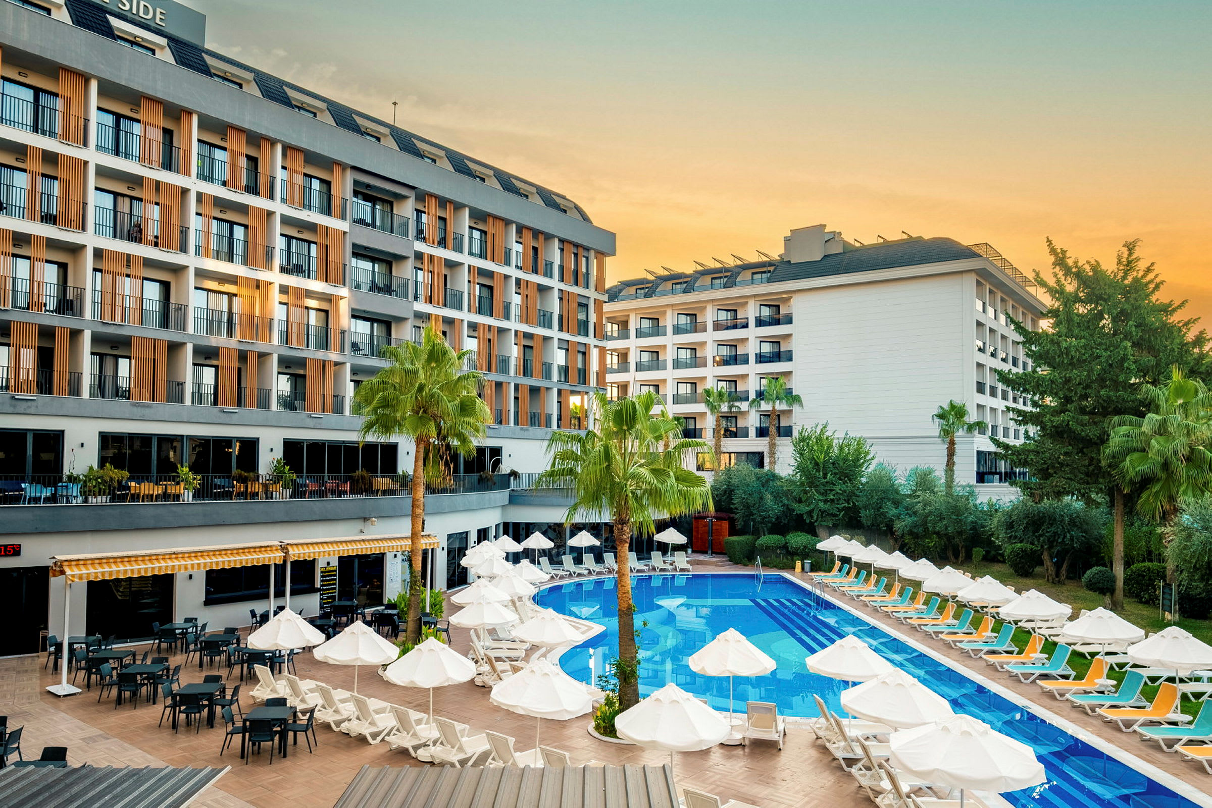 Hotellbygning med bassengområde, solsenger og parasoller. (AI-generert tekst)
