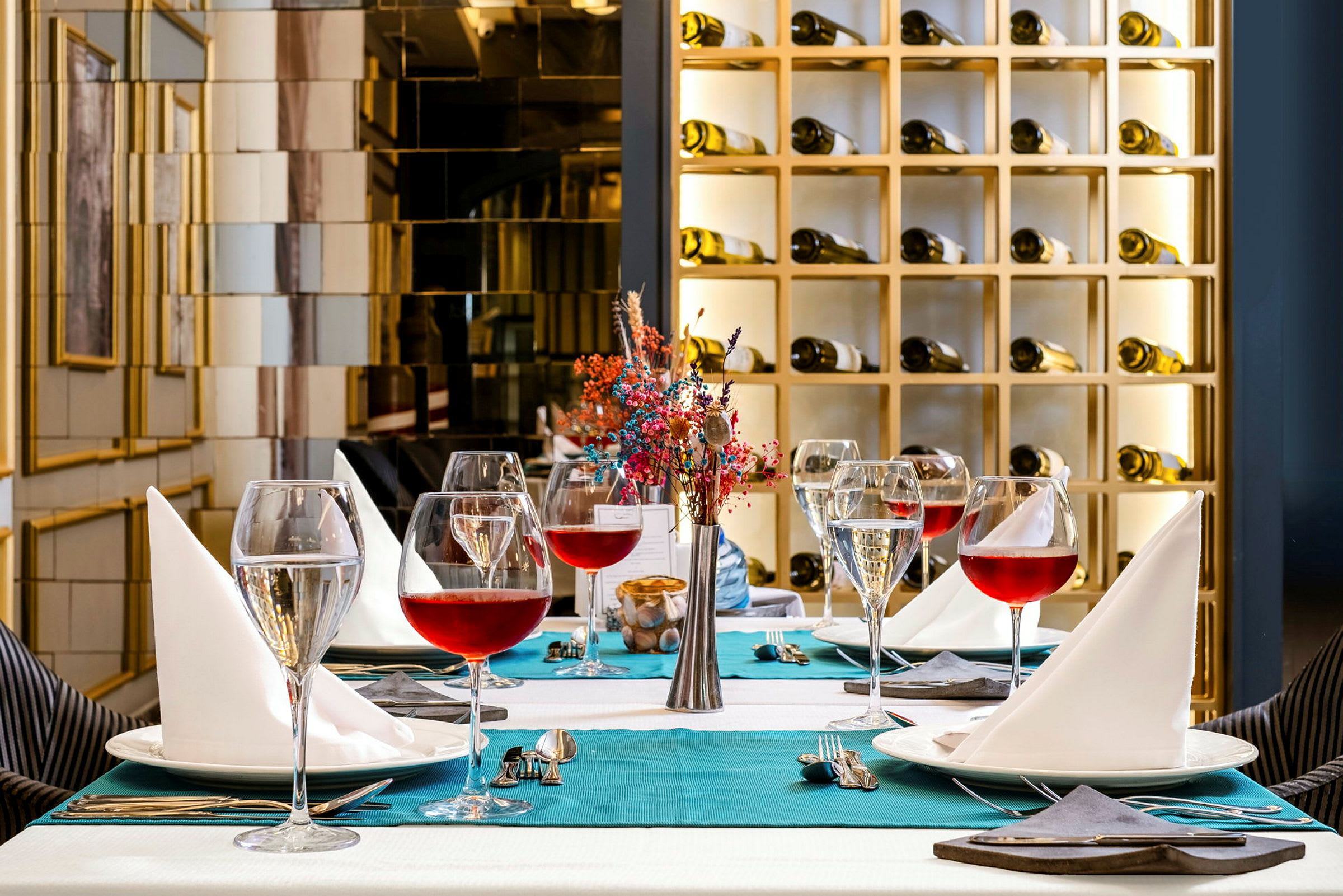 Et elegant dekket bord med vinglass, servietter og en dekorasjon i en fin restaurantmiljø. (AI-generert tekst)