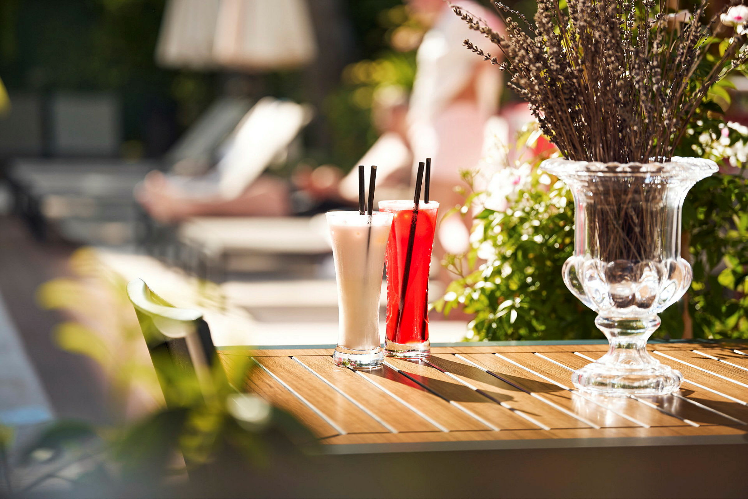 To cocktailglass står på et bord ved siden av en vase med lavendel. (AI-generert tekst)