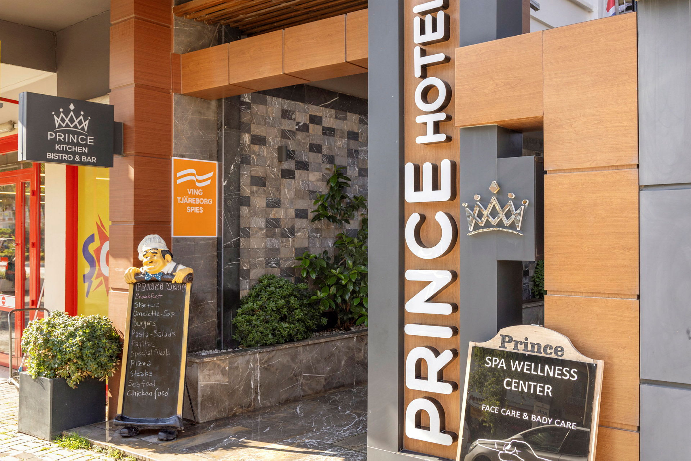 Inngang til Prince Hotel med skilt for restaurant og velværesenter. (AI-generert tekst)