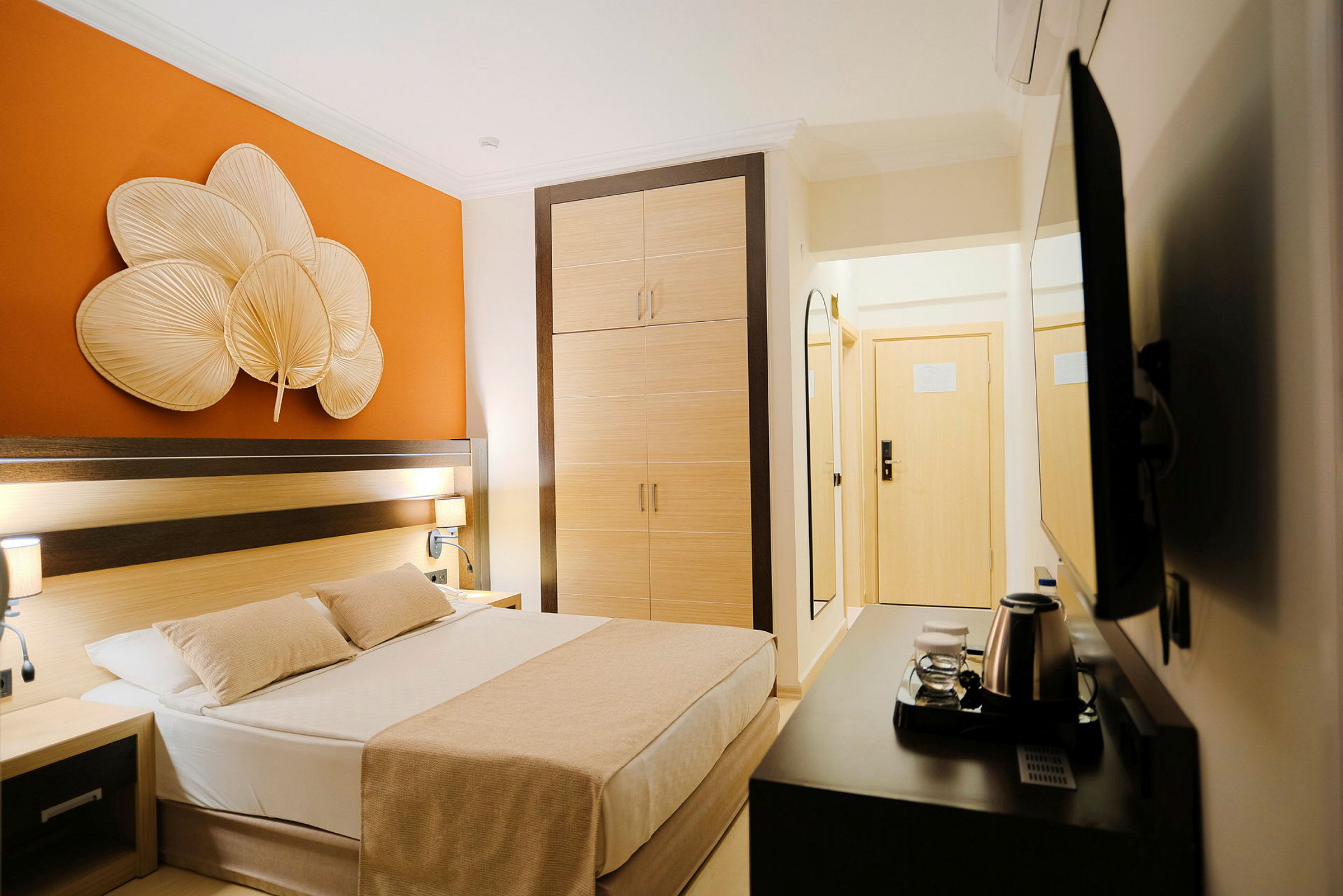 Et hotellrom med en seng, garderobe og oransje veggdekorasjon. (AI-generert tekst)