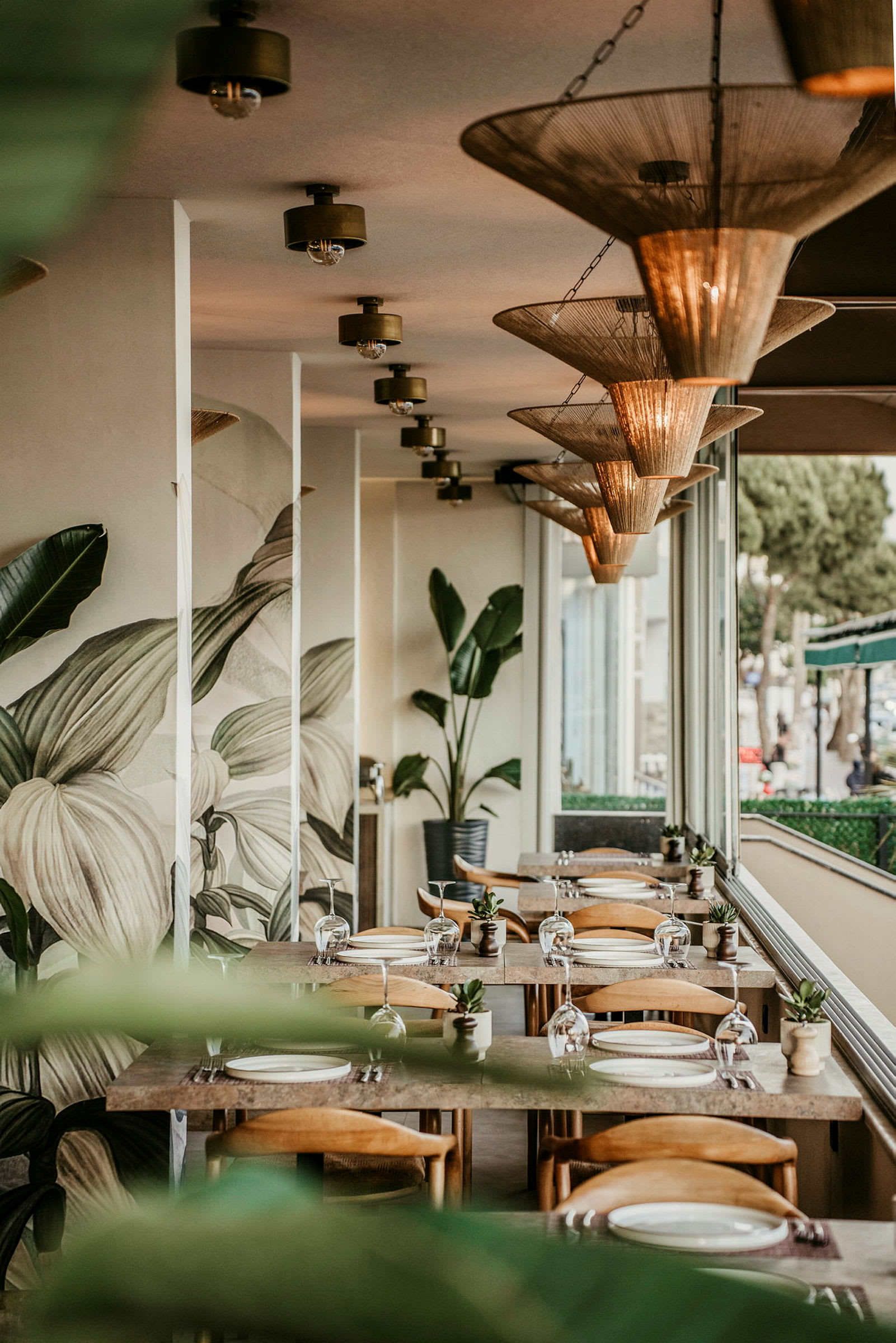 Bilde av en restaurant med bord, stoler og vegg dekorert med planter. (AI-generert tekst)