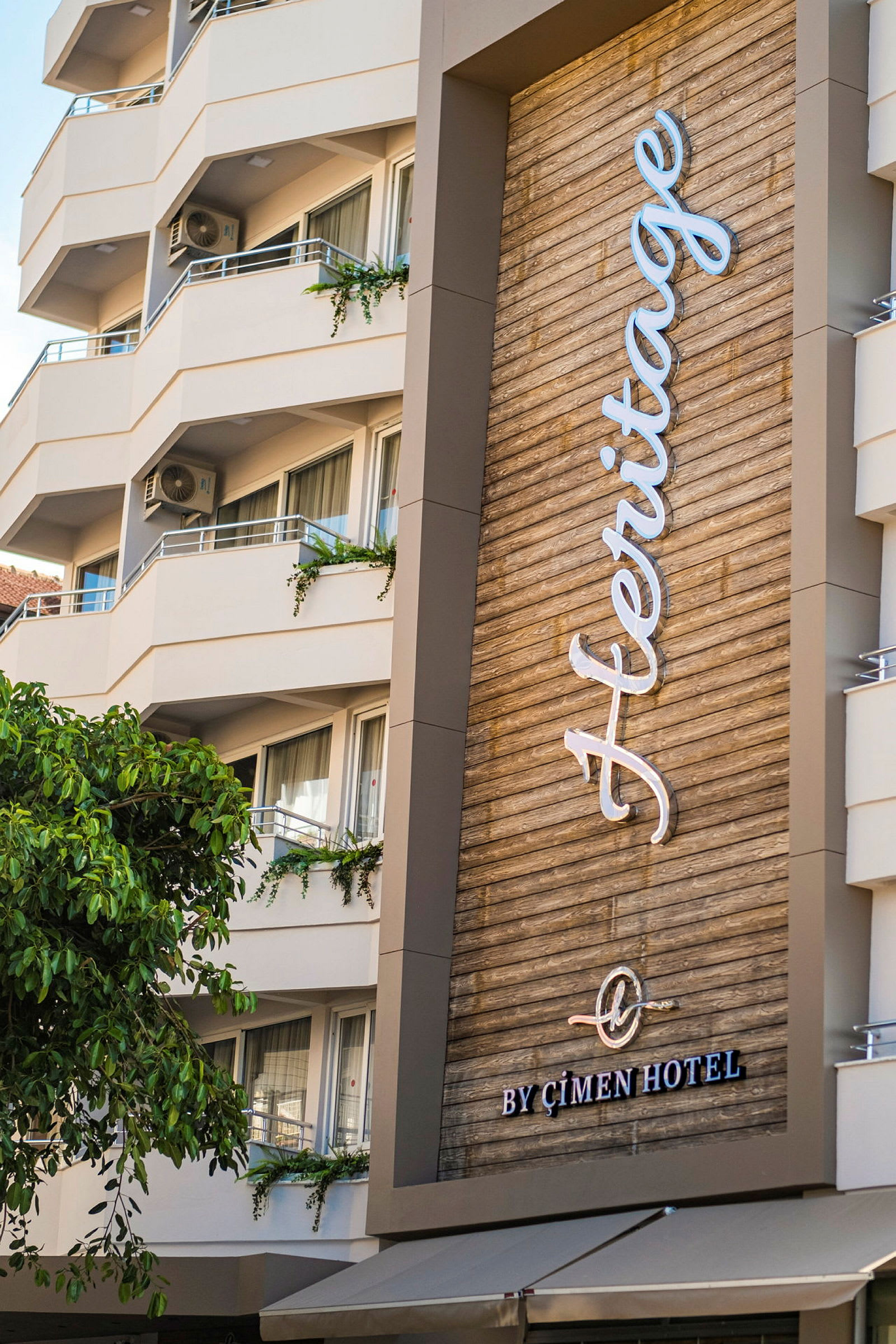 Et moderne hotell med balkonger og et skilt med teksten 'Heritage by Çimen Hotel'. (AI-generert tekst)