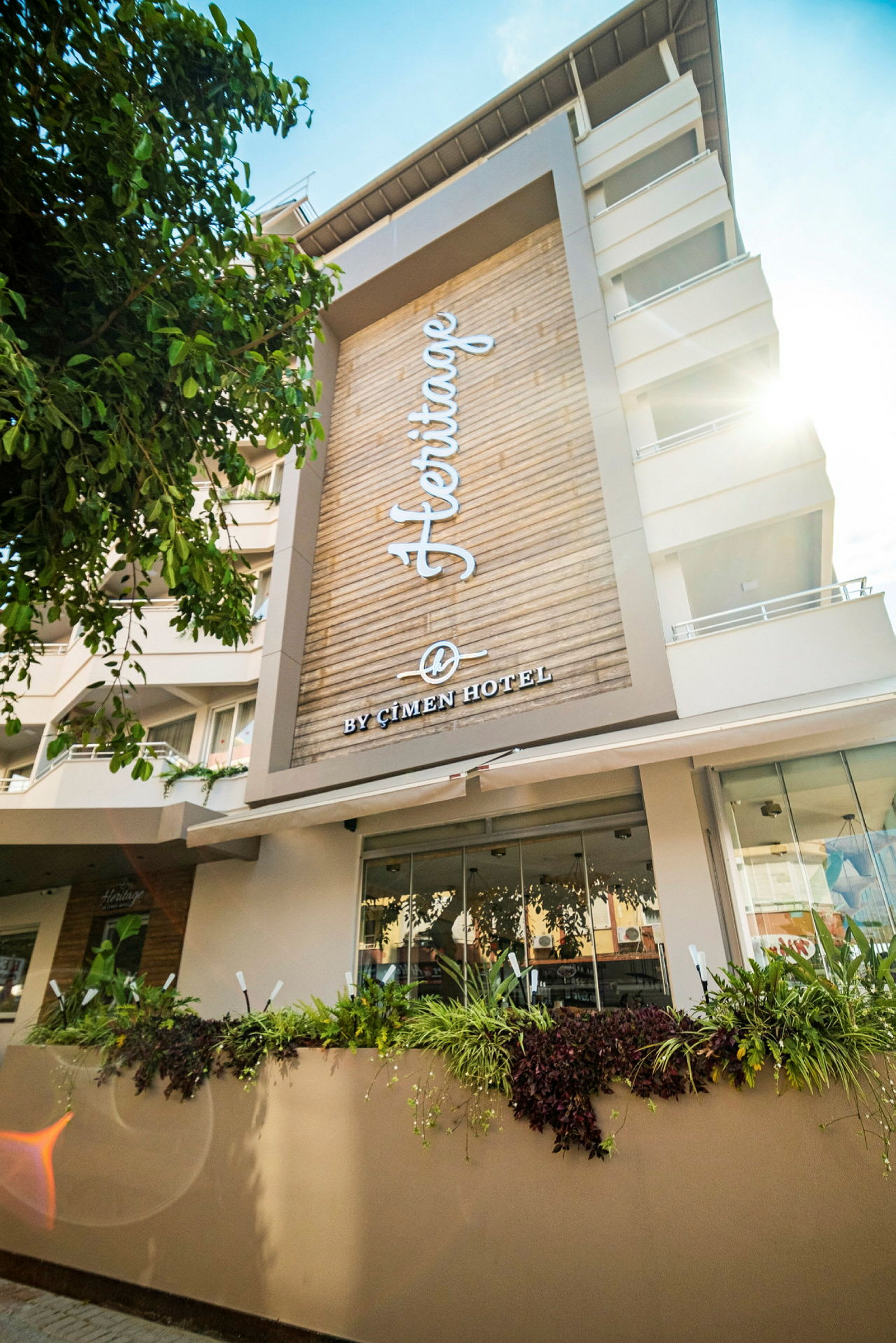 Fasade av Heritage Hotel med teksten 'By Çimen Hotel' synlig på trepanel. (AI-generert tekst)
