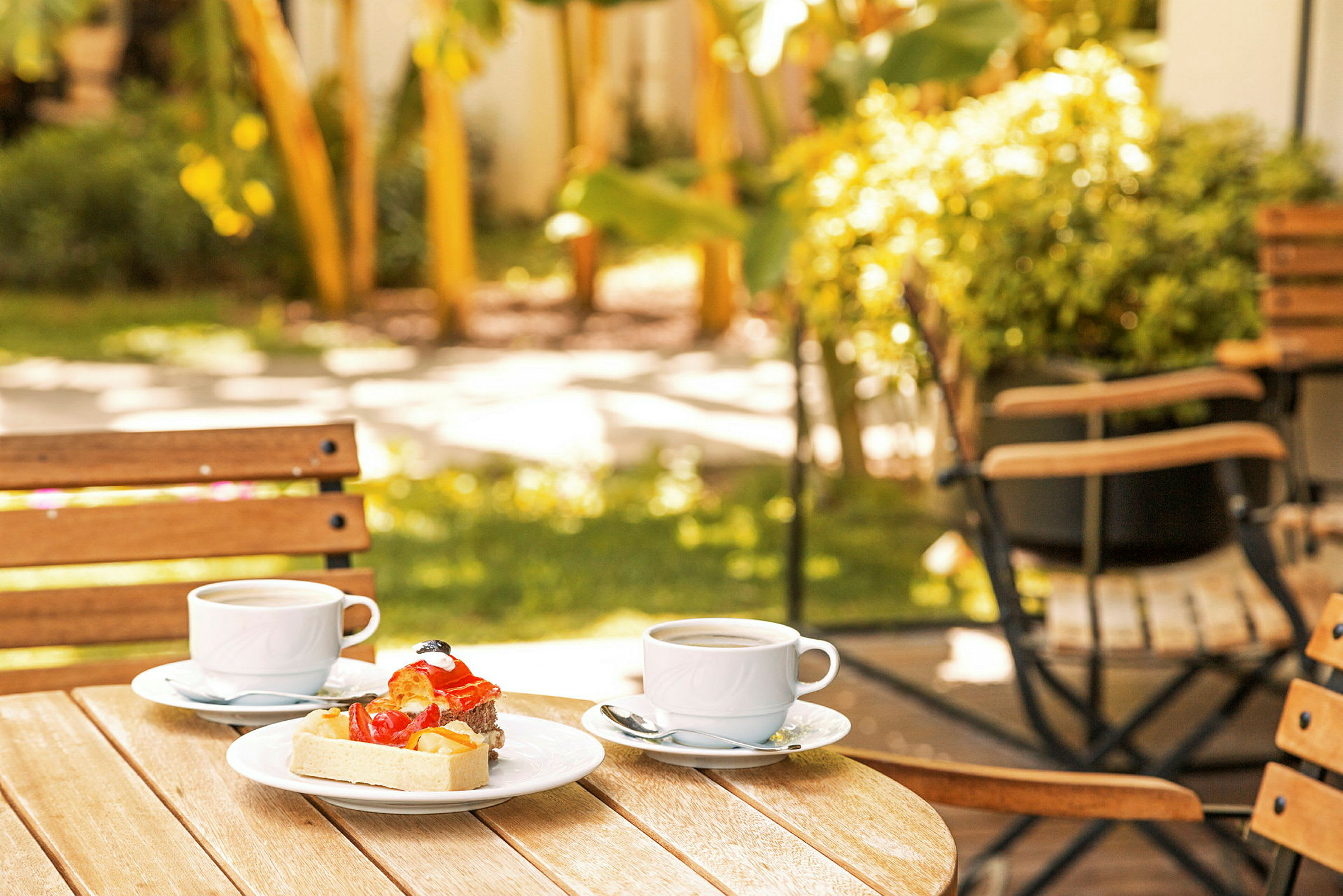 To kaffekopper og dessert på et bord i en hage. (AI-generert tekst)