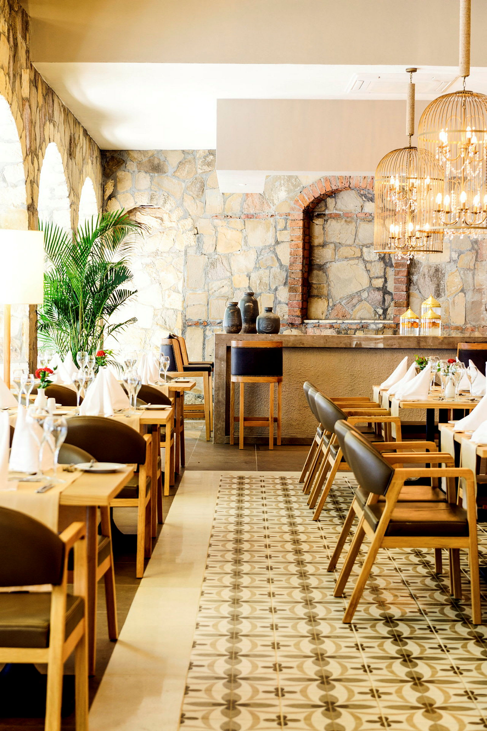 Elegant restaurantinteriør med steinmur, trestoler og bord. (AI-generert tekst)