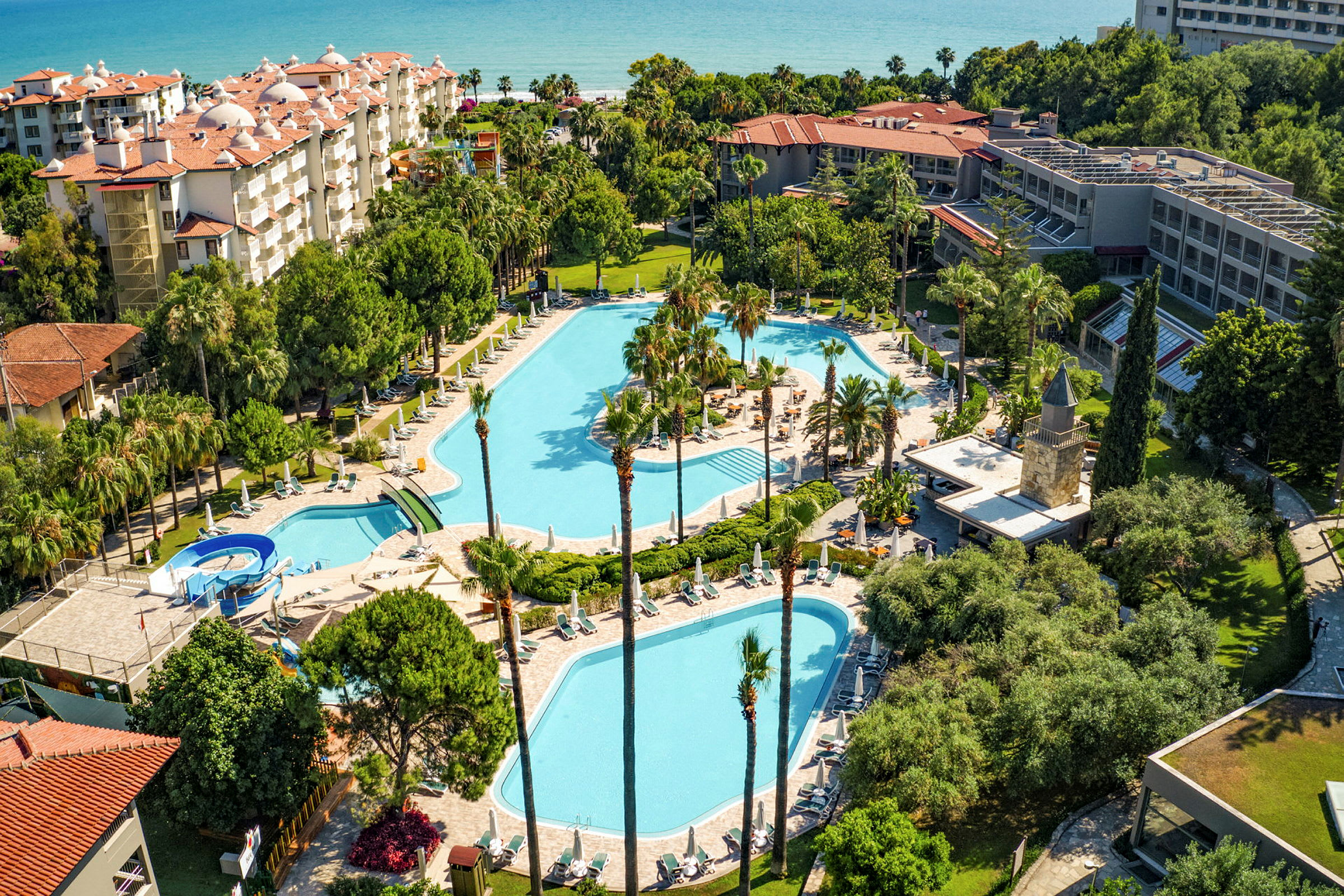 Utsikt over en hotellresort med svømmebassenger omgitt av grøntområder. (AI-generert tekst)