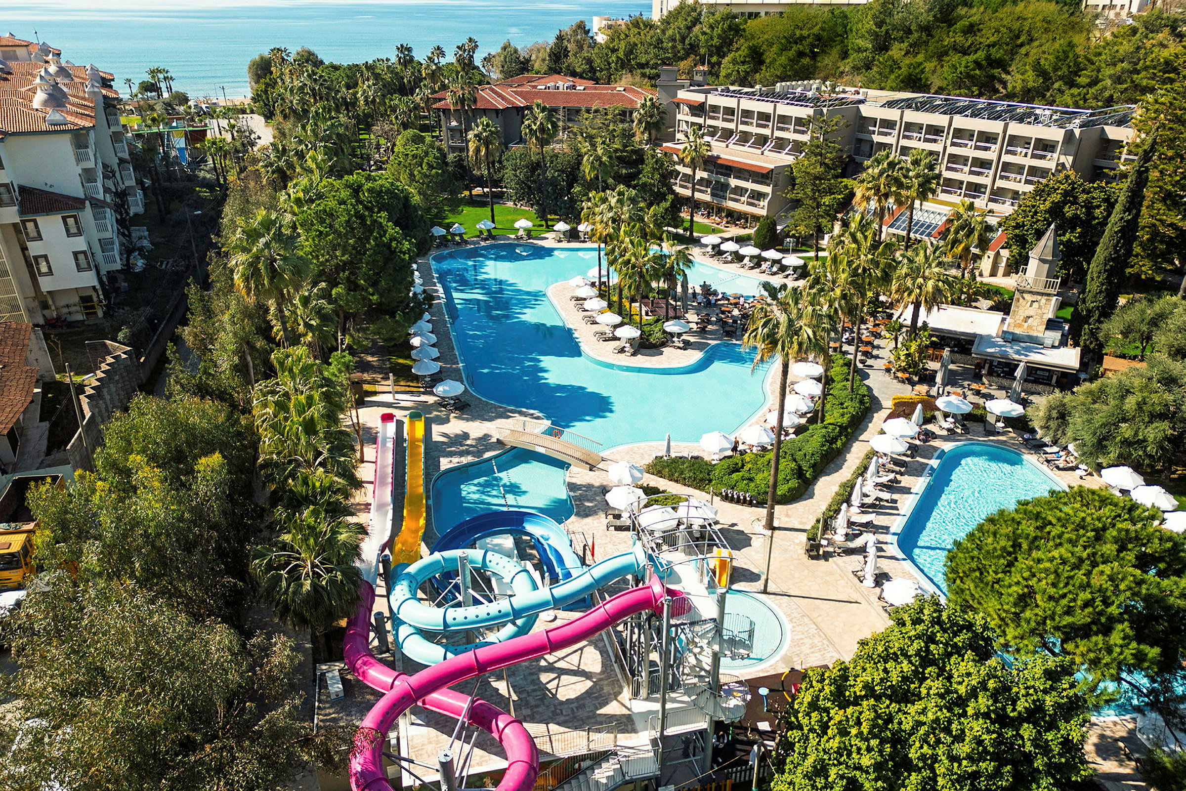 Utsikt over en resort med flere bassenger og vannsklier, omgitt av grøntområder. (AI-generert tekst)