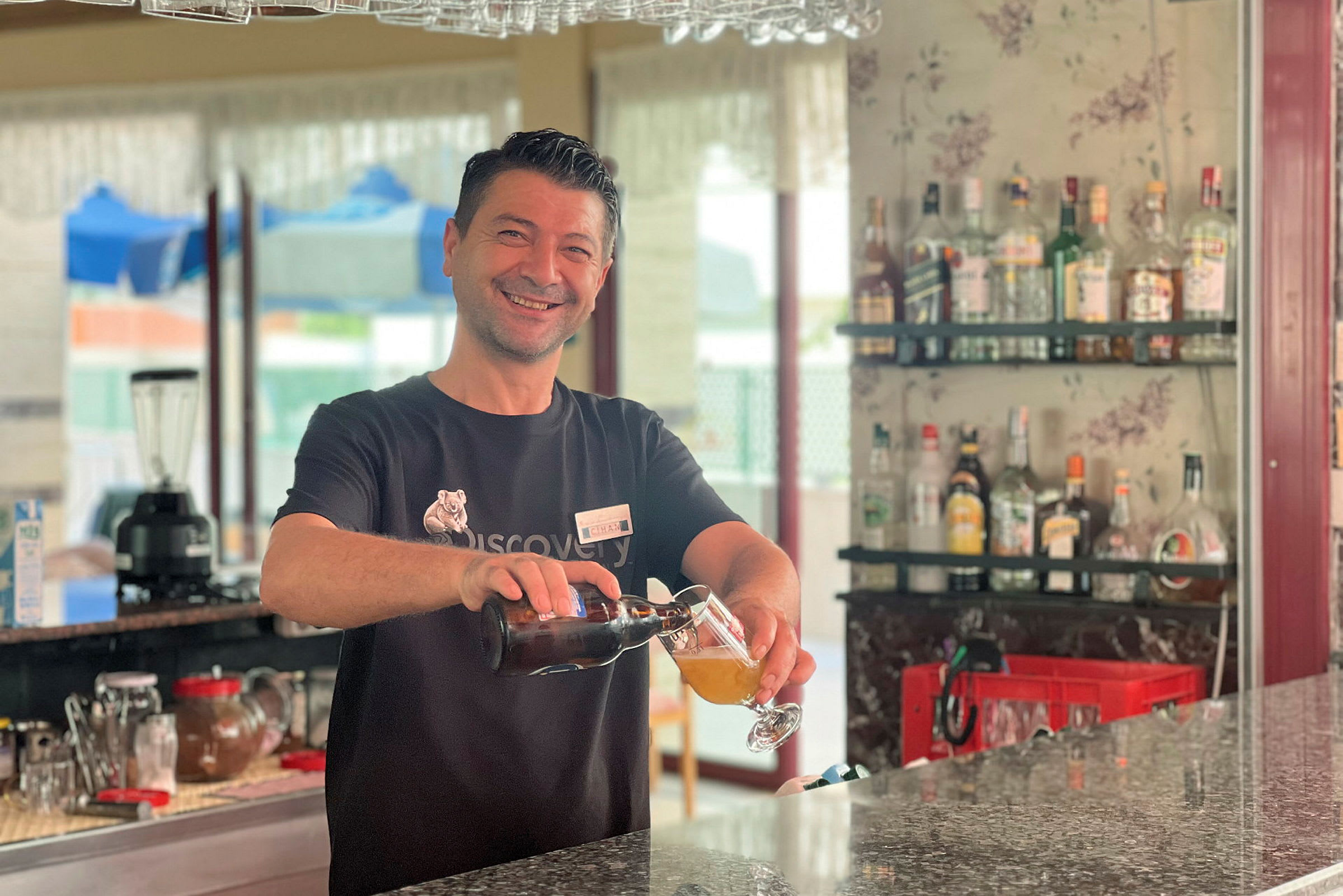En bartender heller opp en drink ved en bar. (AI-generert tekst)