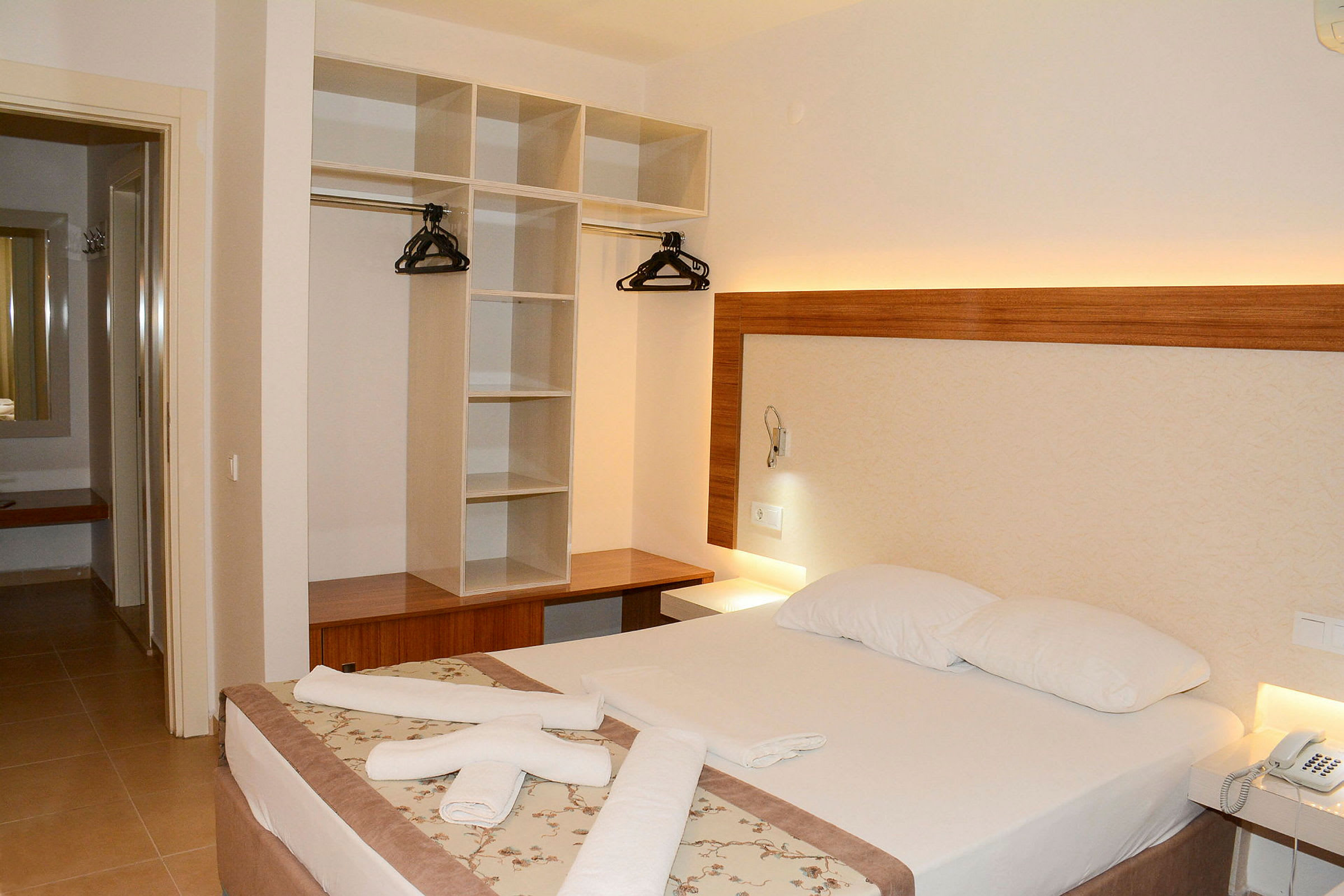 Hotellrom med dobbeltseng, garderobe og nattbord. (AI-generert tekst)