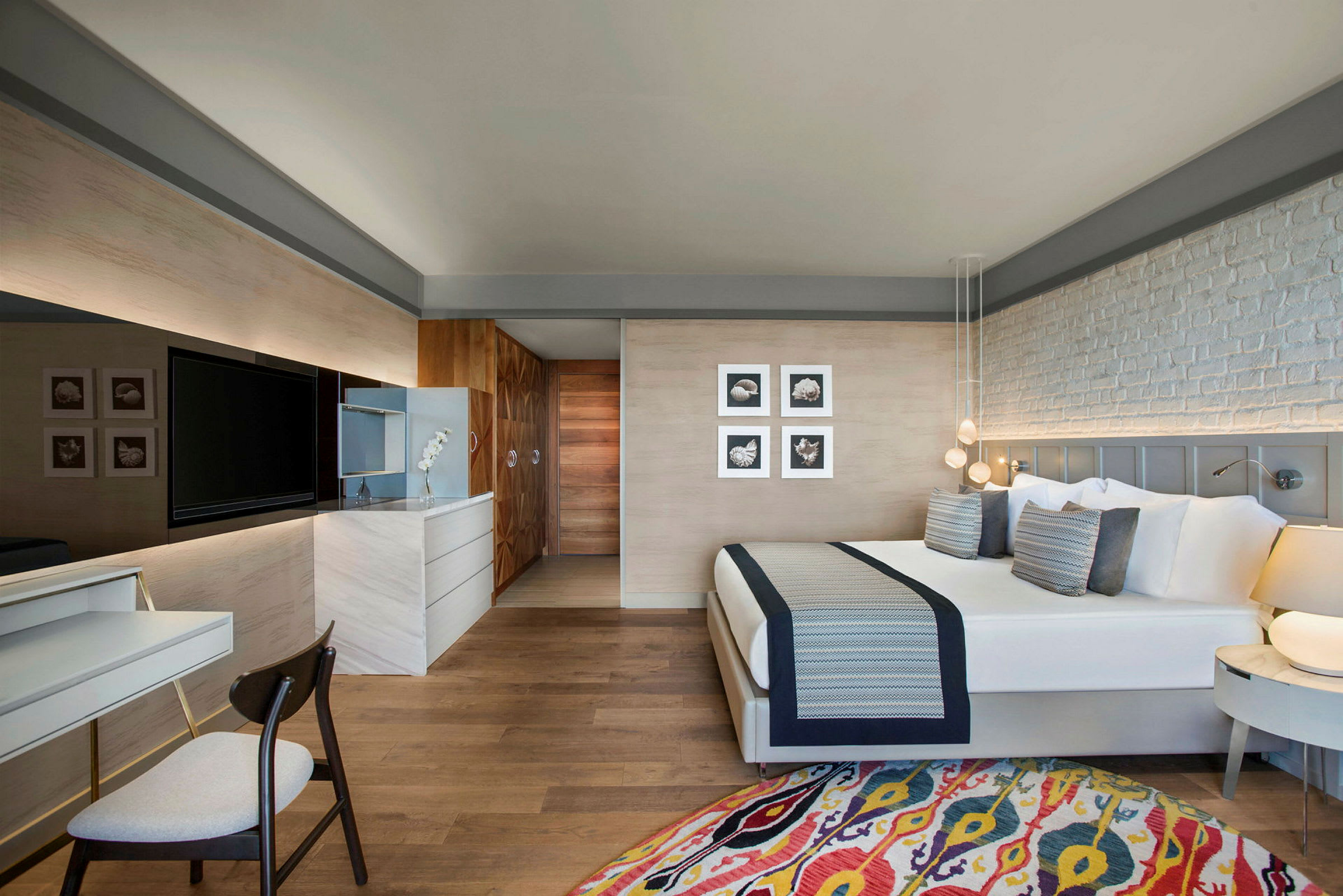 Bilde av et moderne hotellrom med en stor seng, stol, skrivebord og TV. (AI-generert tekst)