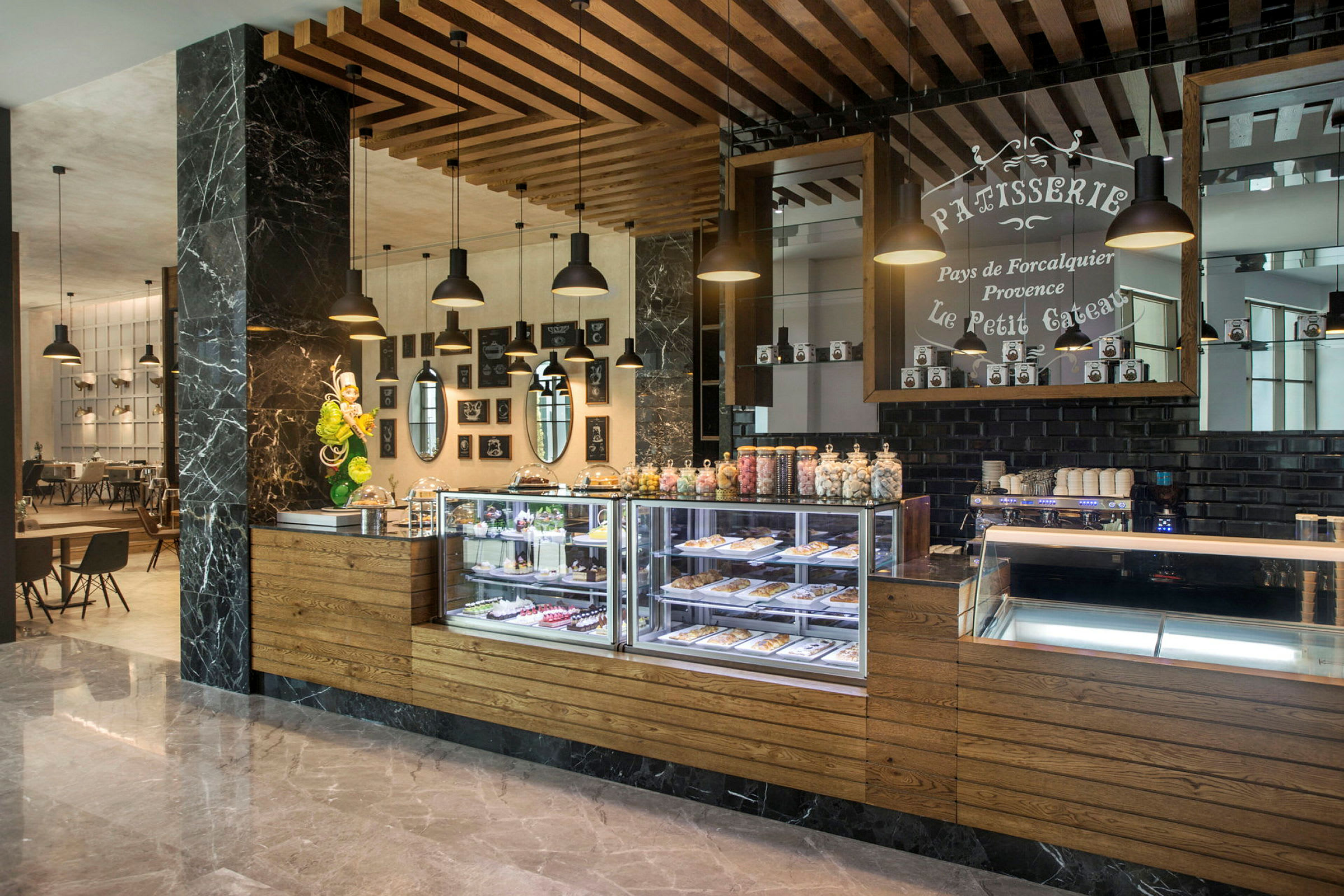 Bilde av en kafé med glassmonter med bakverk og dekorative detaljer på veggene. (AI-generert tekst)