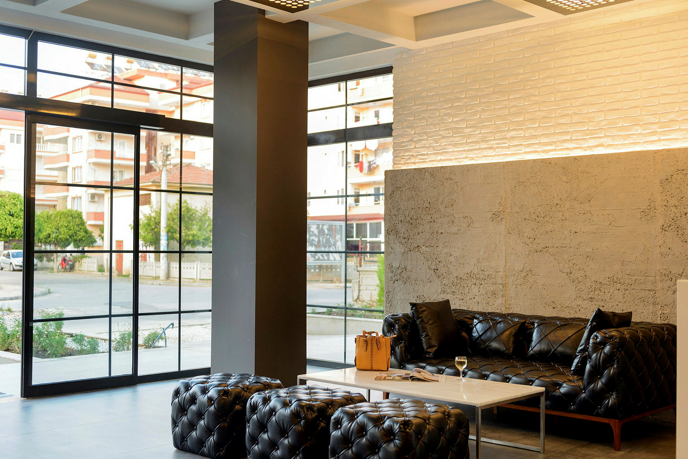 Moderne lobby med svarte sofaer, et marmorbord og store vinduer. (AI-generert tekst)