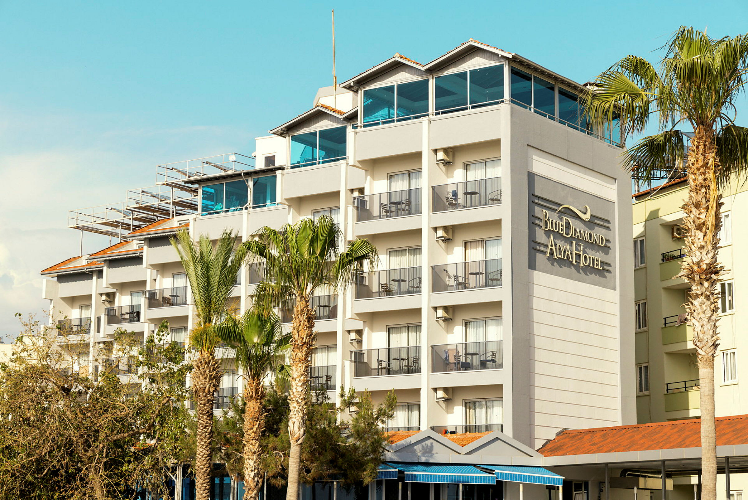 En hotellbygning med flere etasjer og balkonger, og teksten "Blue Diamond Alya Hotel" på veggen. (AI-generert tekst)