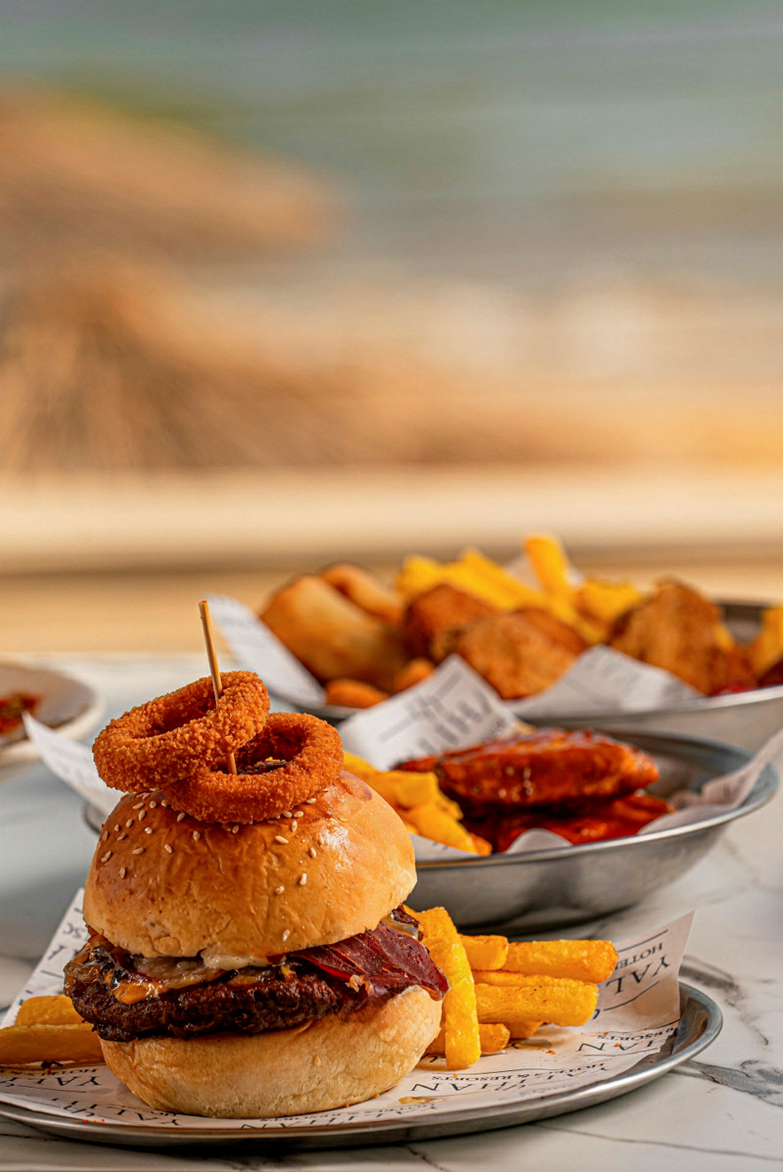 En hamburger med løkringer og pommes frites på en tallerken. (AI-generert tekst)