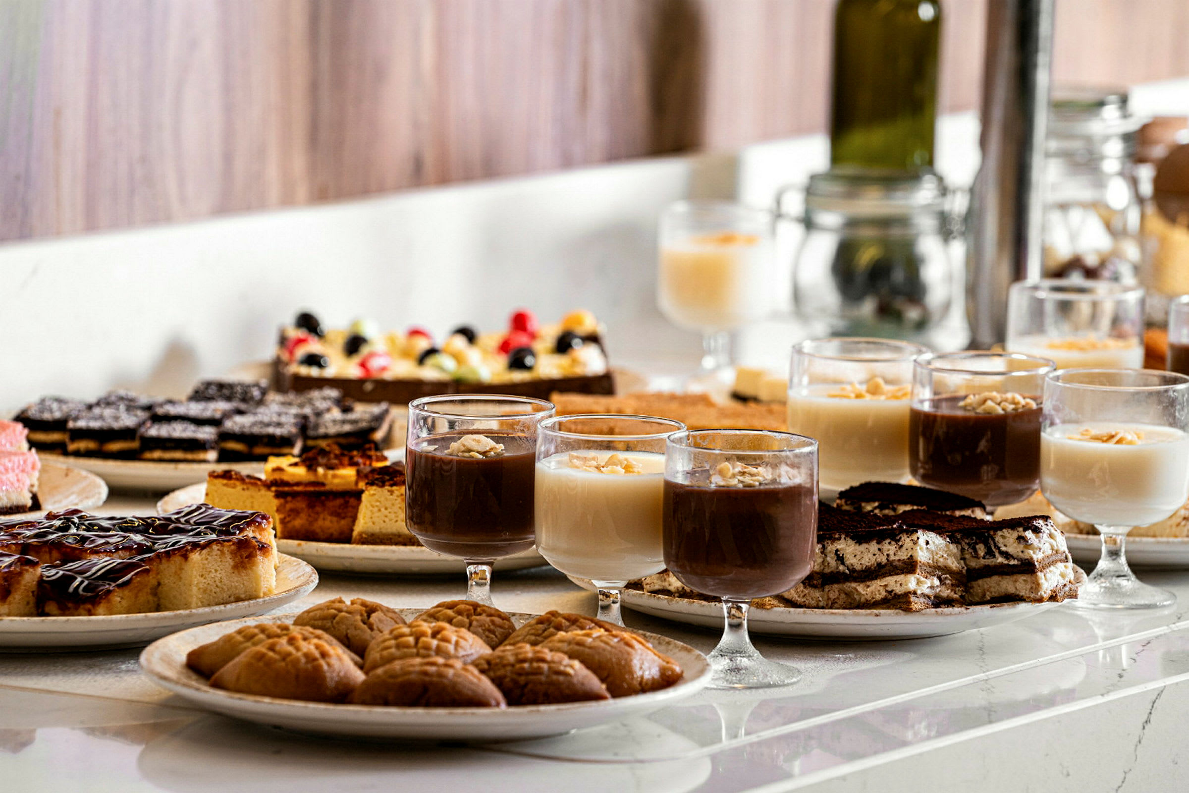 Et bord med ulike desserter, inkludert glass med mousse og bakverk. (AI-generert tekst)