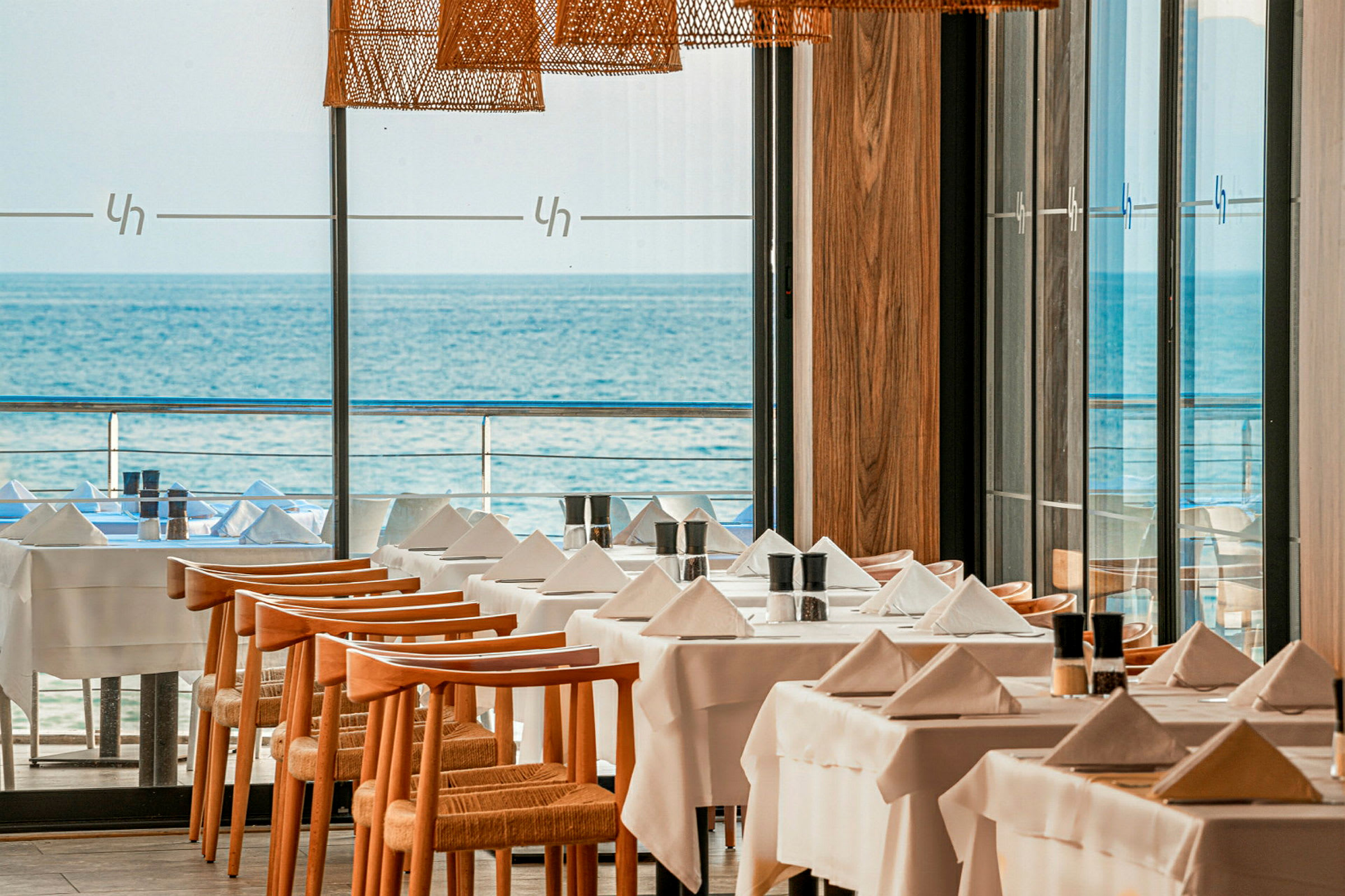 Et restaurantområde med dekkede bord og utsikt over havet. (AI-generert tekst)