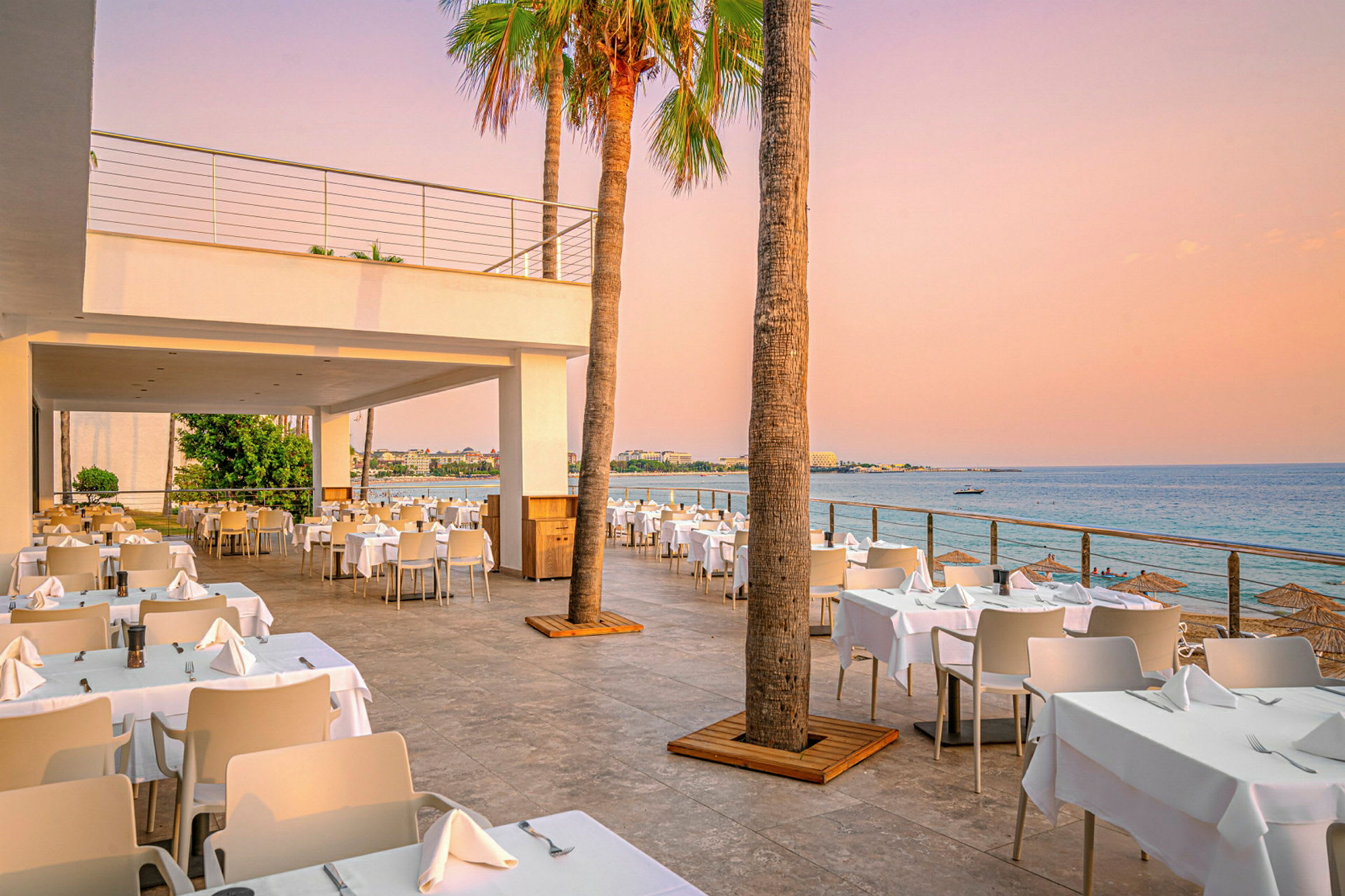 Utendørs restaurant med havutsikt ved solnedgangen. (AI-generert tekst)