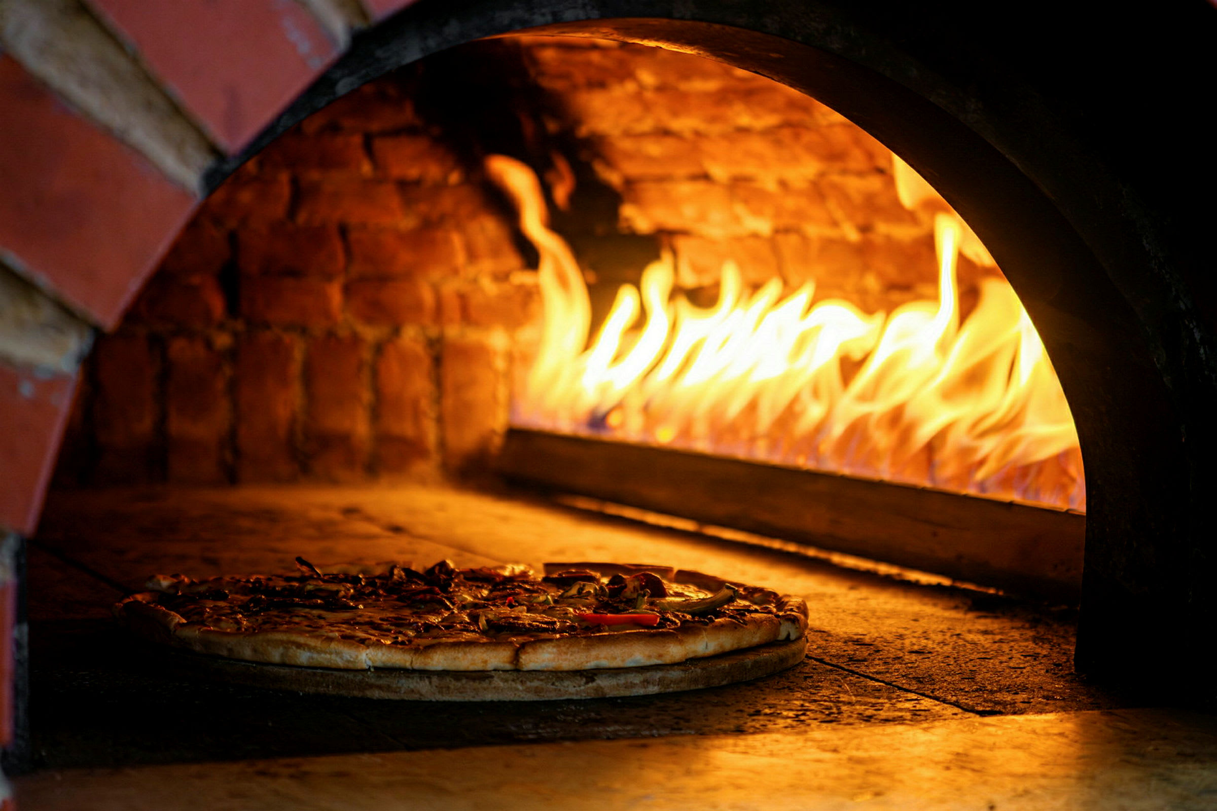 Vedfyrt ovn med en pizza som stekes. (AI-generert tekst)
