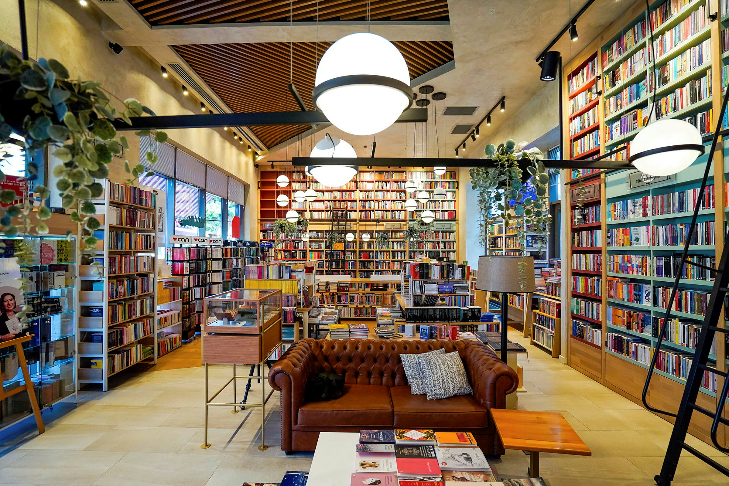 Et velorganisert bibliotek eller bokhandel med en brun sofa og mange bokhyller fylt med bøker. (AI-generert tekst)
