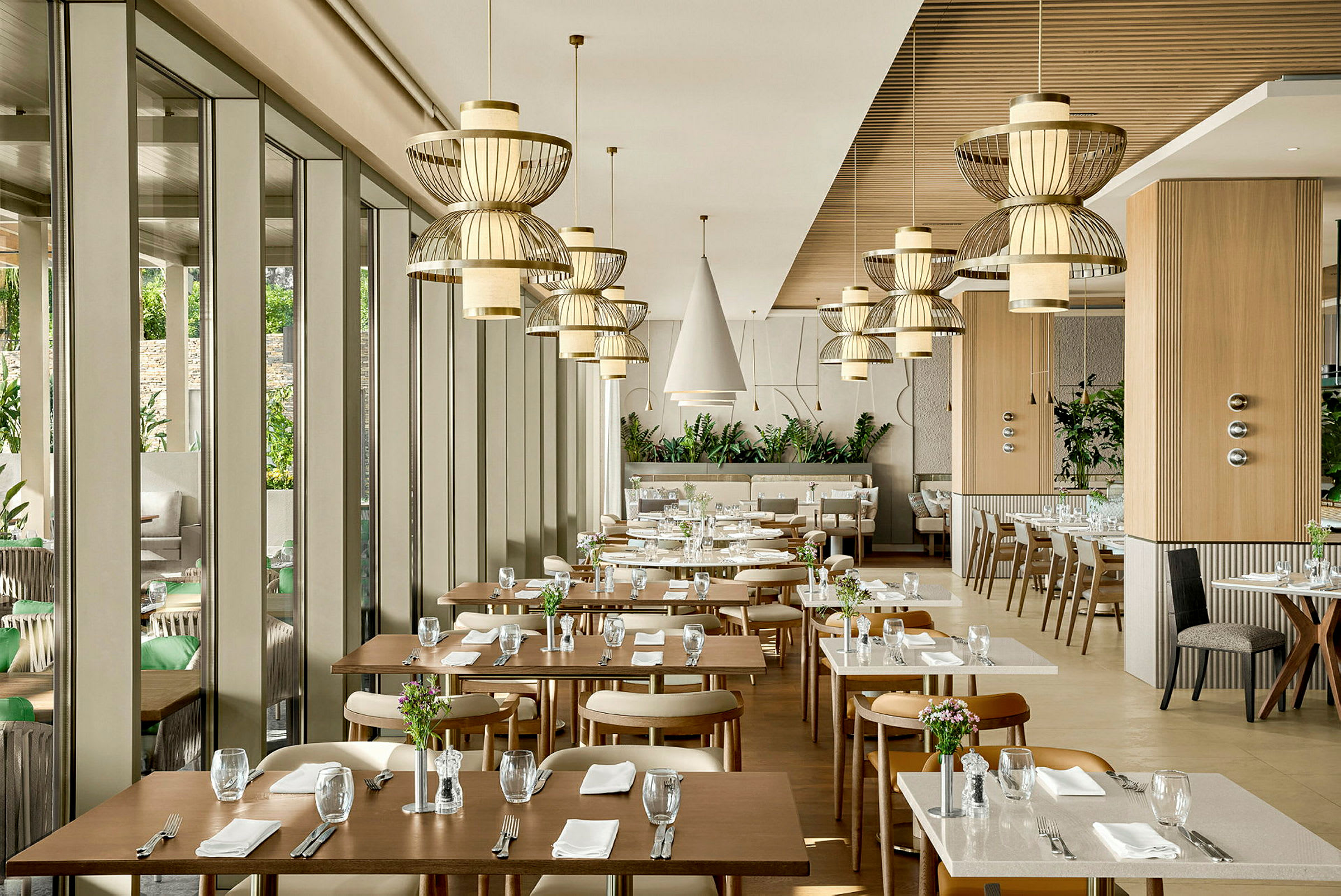 En moderne restaurant med elegante bord og stoler samt dekorative taklamper. (AI-generert tekst)