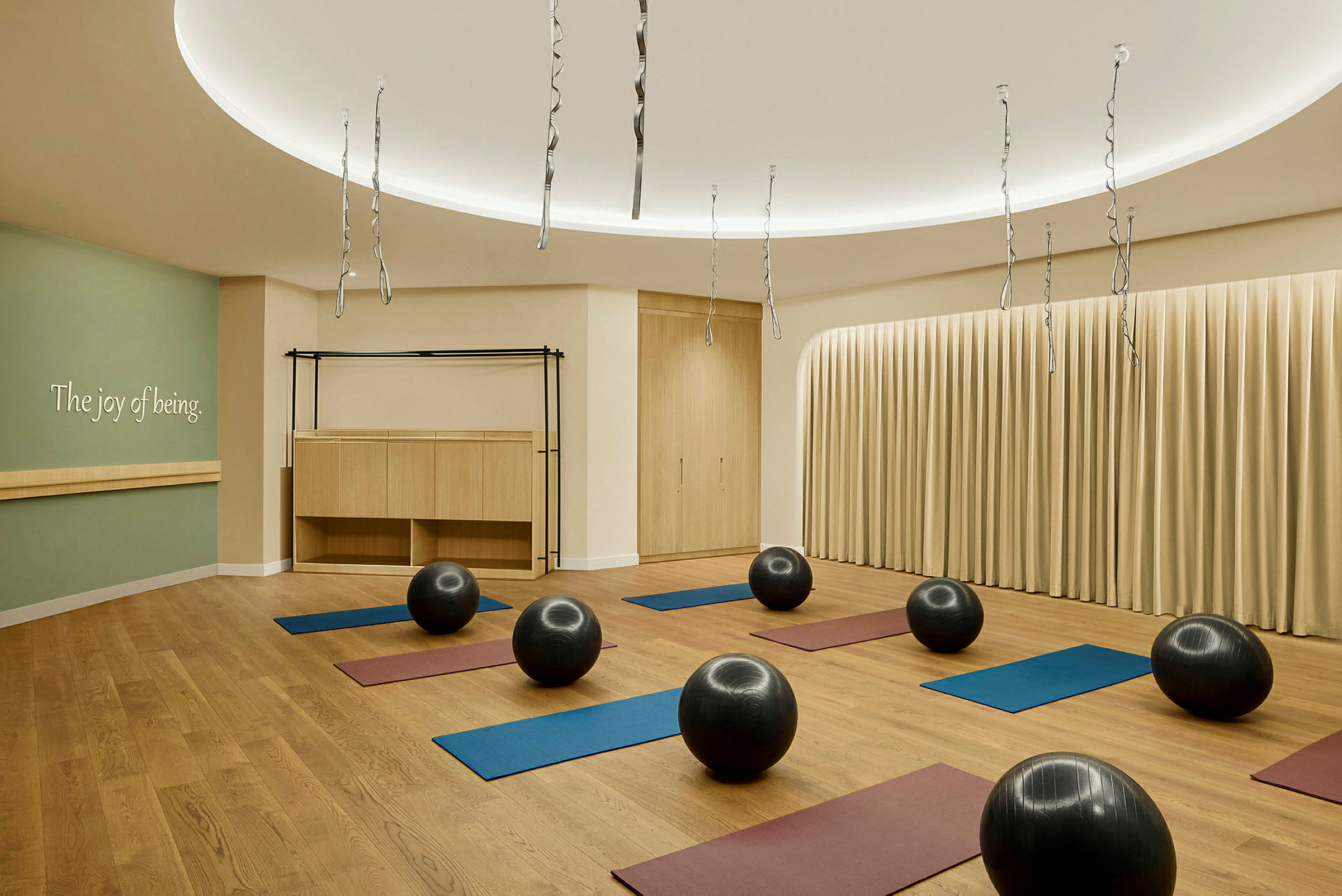 Et yoga- eller treningsrom med treningsmatter og balanseballer jevnt spredt på et tregulv. (AI-generert tekst)