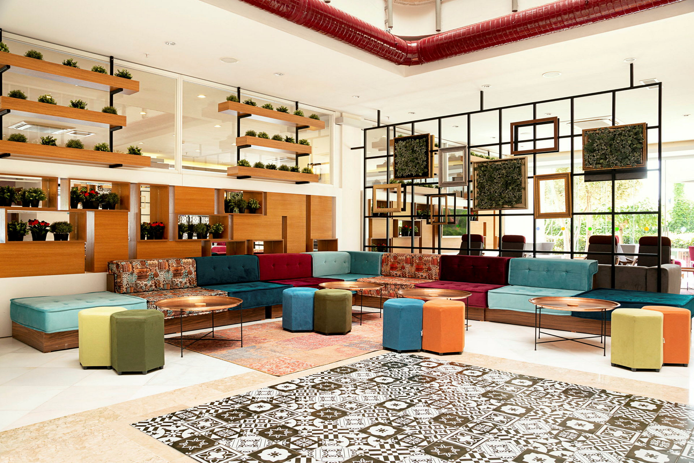 Bilde av en stilfullt innredet lounge med fargerike sofaer, sittepuffer og veggdekorasjoner. (AI-generert tekst)
