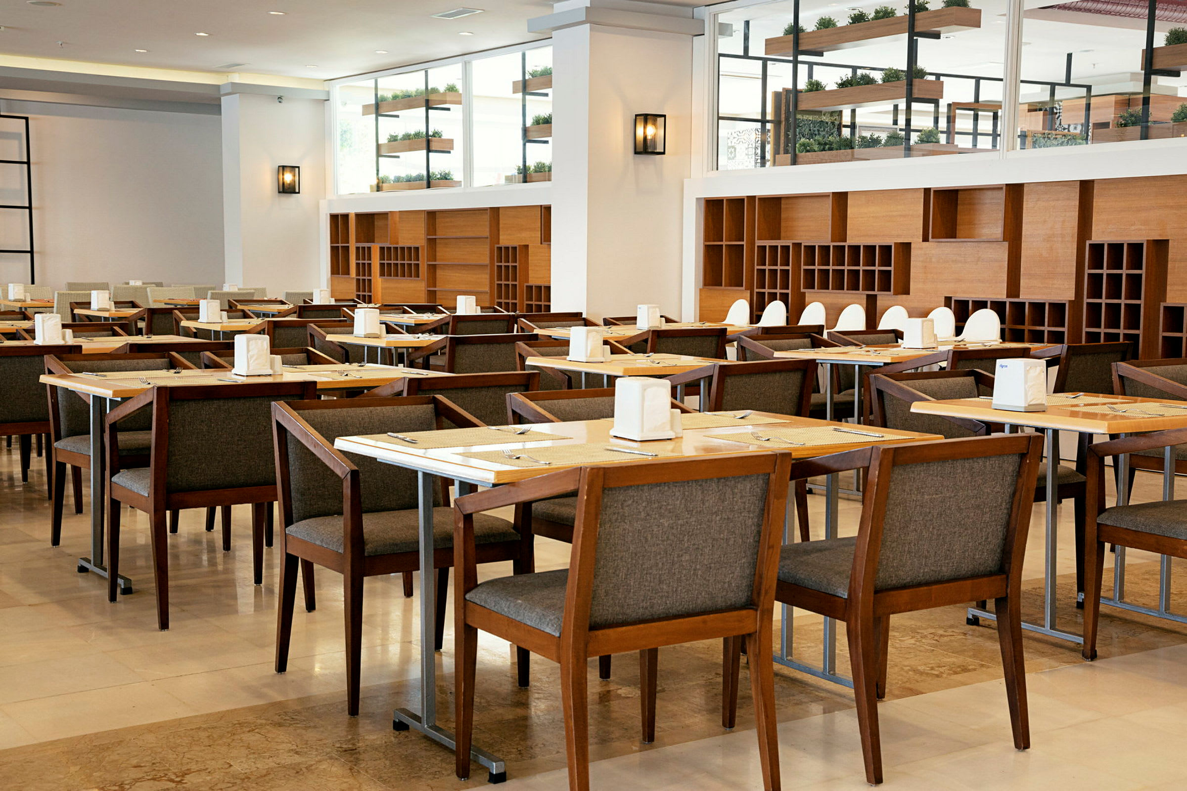 Restaurant med flere bord og stoler av tre, innredet med hyller og dekorasjoner. (AI-generert tekst)