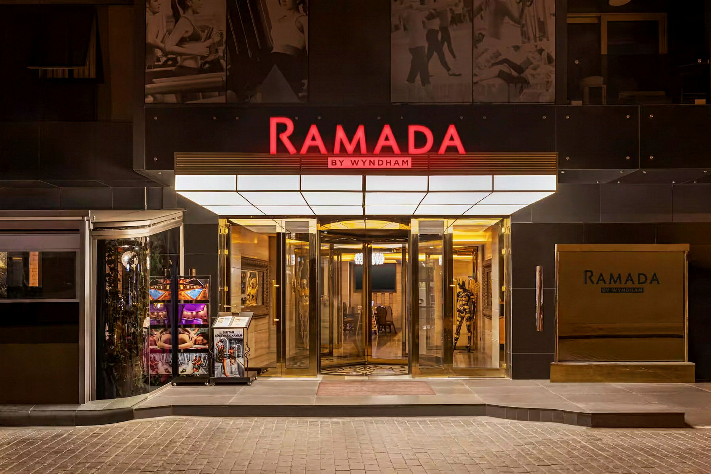 Hovedinngangen til hotellkjeden Ramada by Wyndham, med en roterende dør og skilt. (AI-generert tekst)